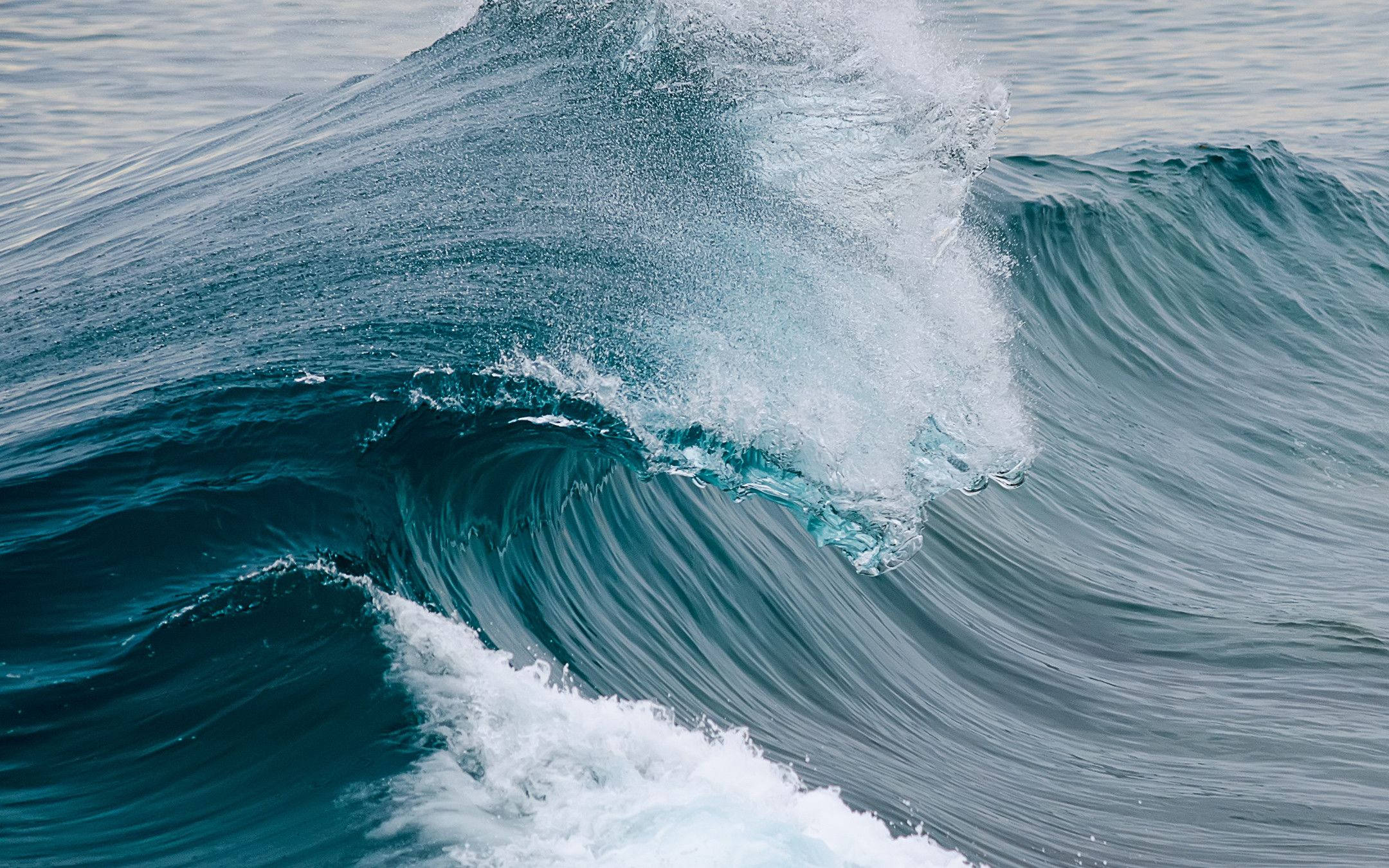 Wave 桌布 壁紙 — 一道強勁的海浪捲起並破碎，帶著泡沫般的白色浪花，衝擊深藍綠色的海水。