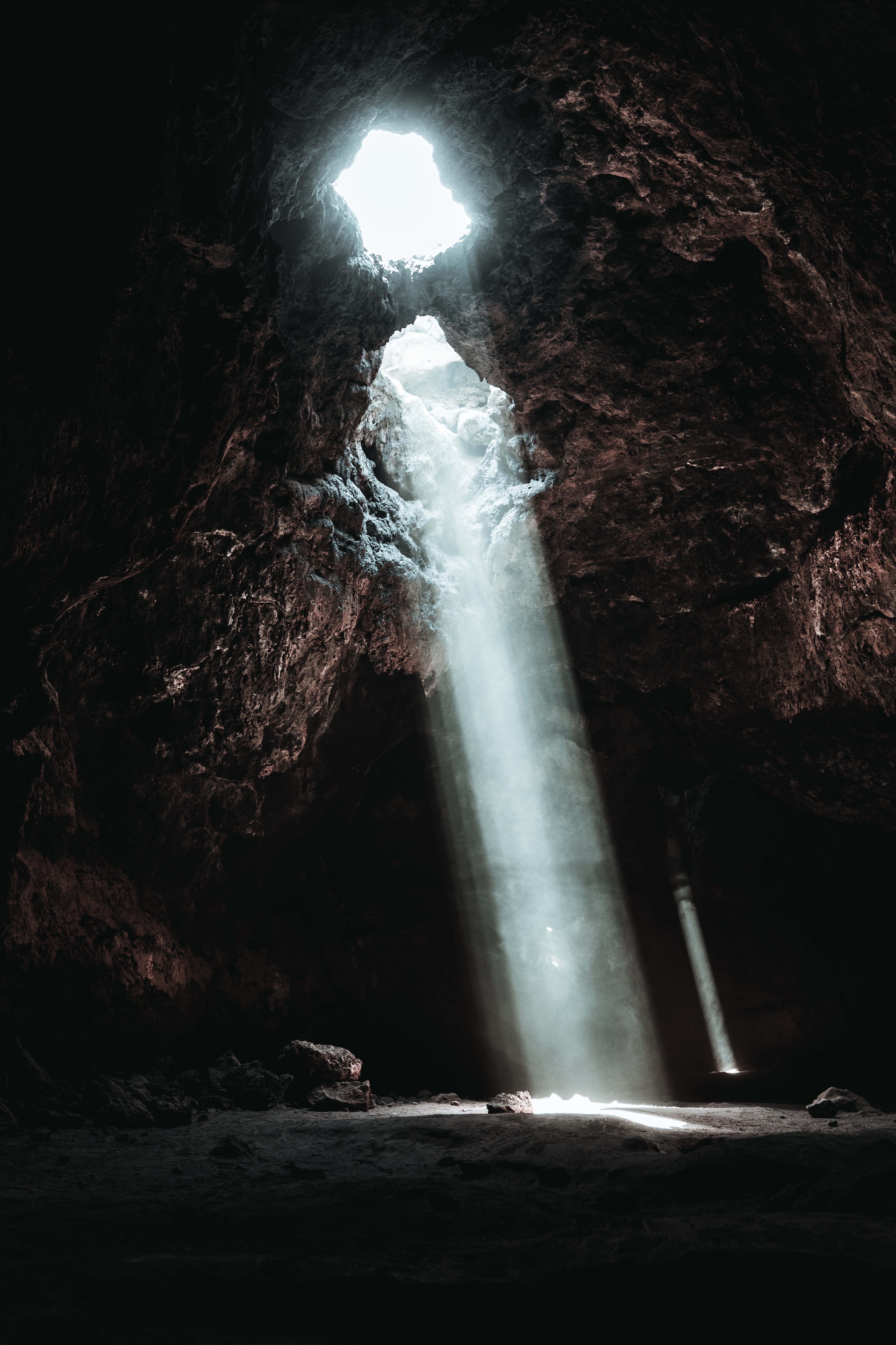 Cave 桌布 壁紙 — 一道強勁的瀑布從黑暗的洞穴中傾瀉而下，明亮的陽光從上方的高處開口照射進來。