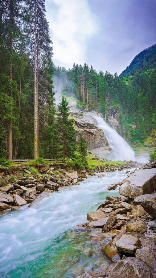 Austria 桌布 壁紙 — 一道強勁的瀑布穿過茂密的綠色森林，霧氣升騰，藍綠色的水流衝過岩石。