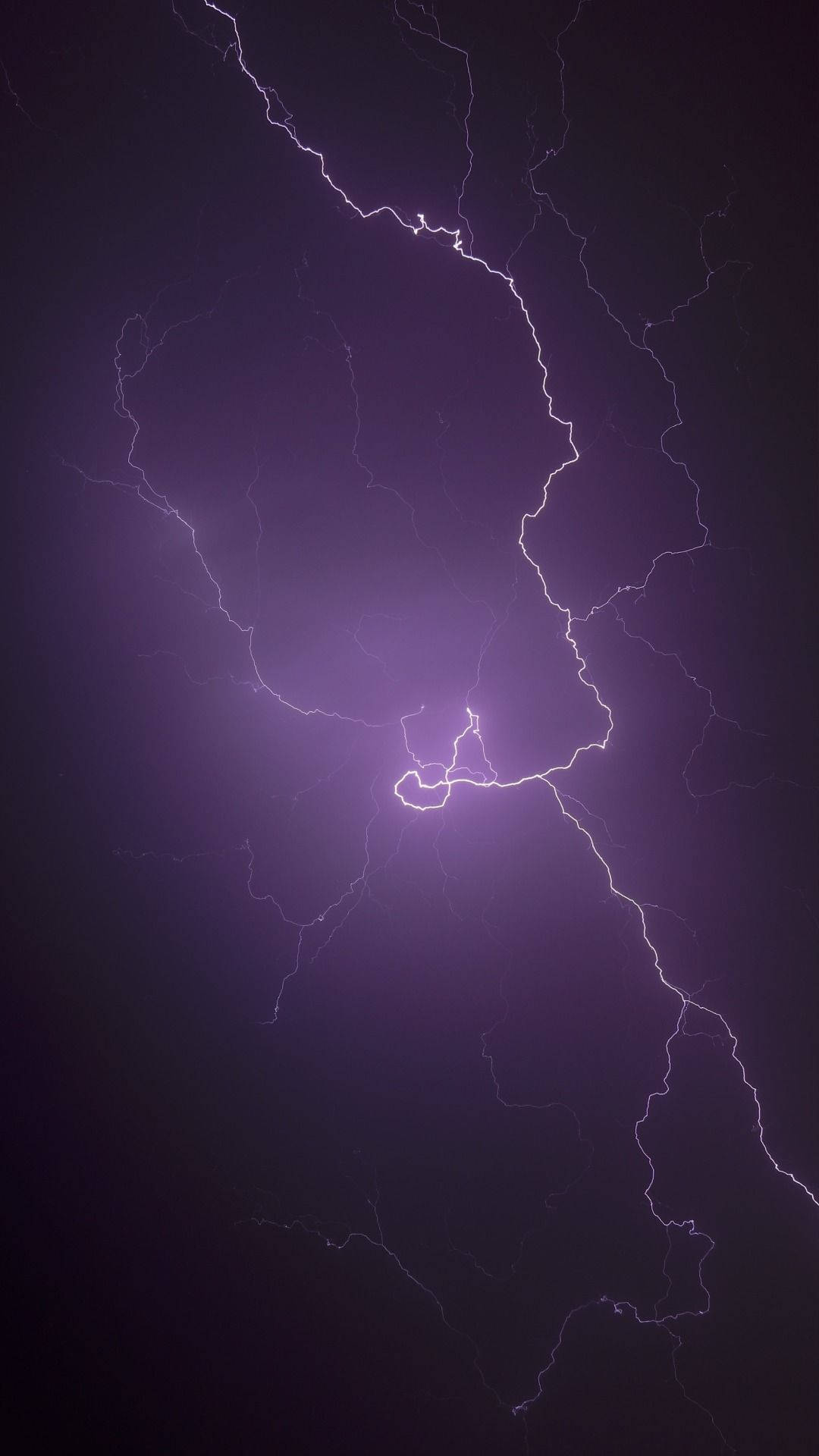 Aesthetic Lightning 桌布 壁紙 — 一道強勁的紫色閃電在黑暗的暴風雨天空中分叉，形成戲劇性的自然景觀。
