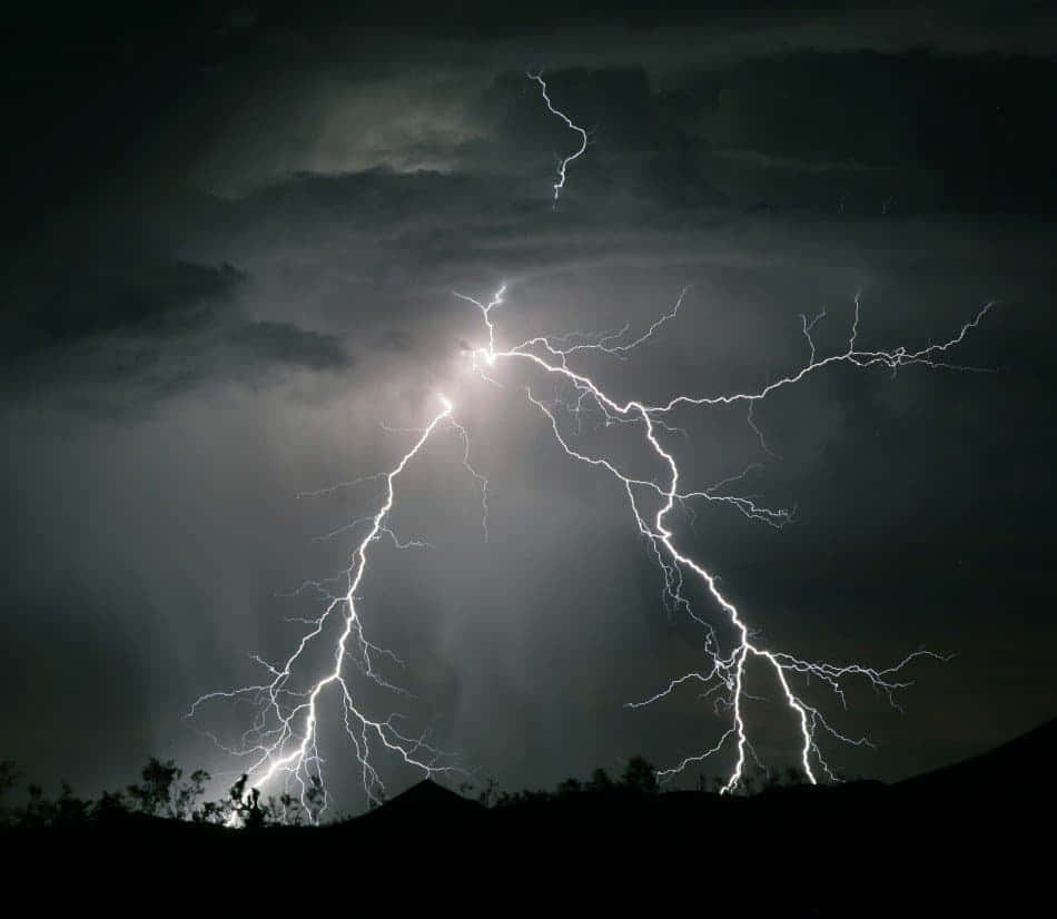 閃電 桌布 壁紙 — 一道強勁的閃電在黑暗山丘剪影上方的暴風雨夜空中分叉。