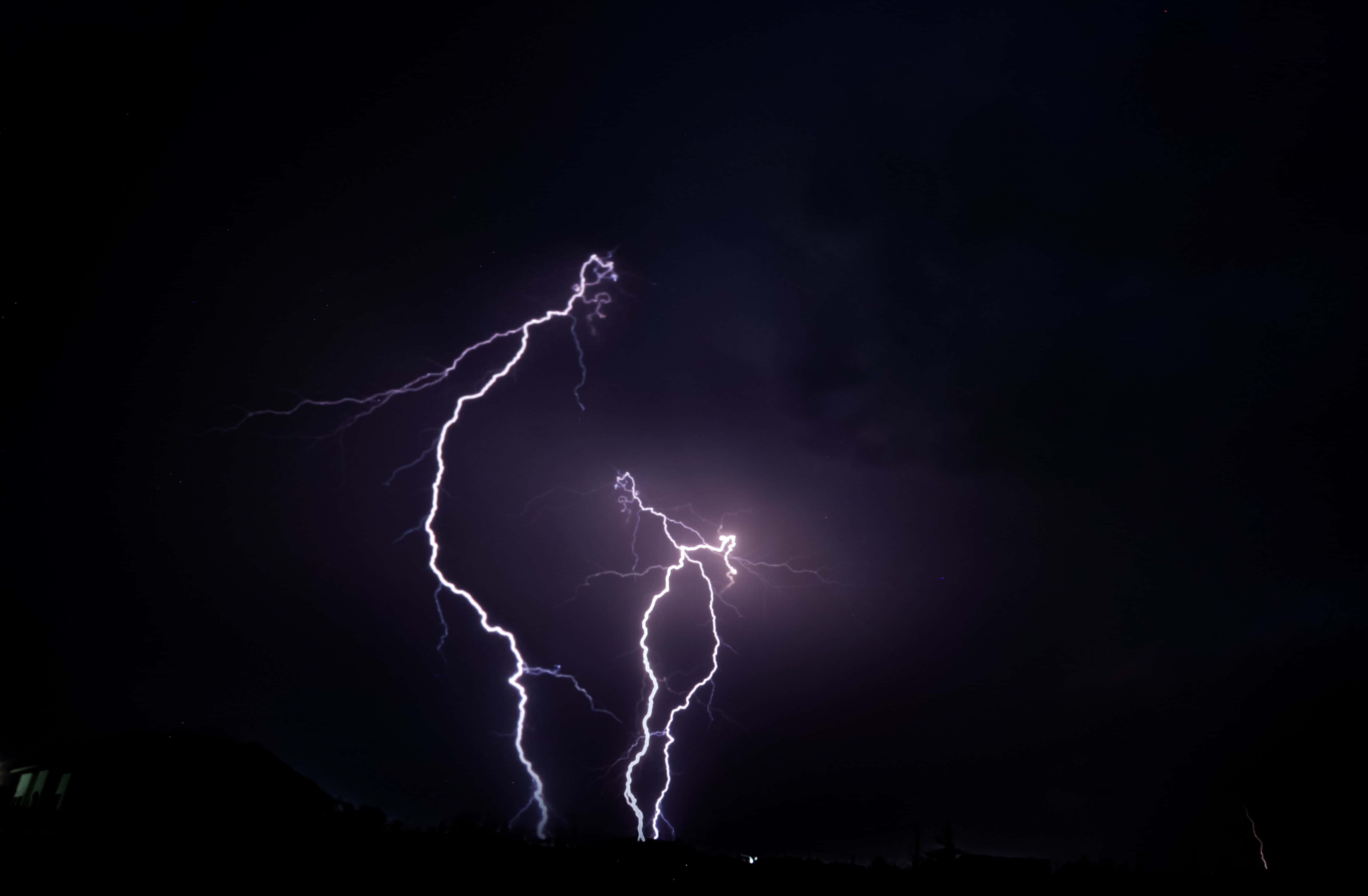 Lightning Bolt 桌布 壁紙 — 一道強勁的閃電在黑暗的夜空中分叉，劃過剪影般的地景。