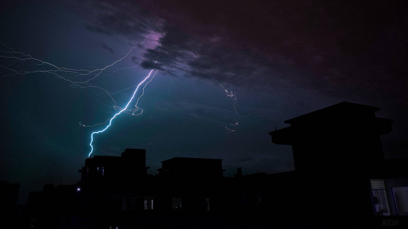 Silhouette 桌布 壁紙 — 一道強大的閃電在暴風雨的夜空中分叉，劃過剪影般的城市屋頂。