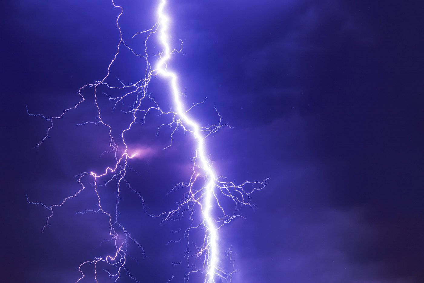 Storm 桌布 壁紙 — 一道強大的閃電在深紫色暴風雨天空中分叉，帶有生動的電光觸鬚。