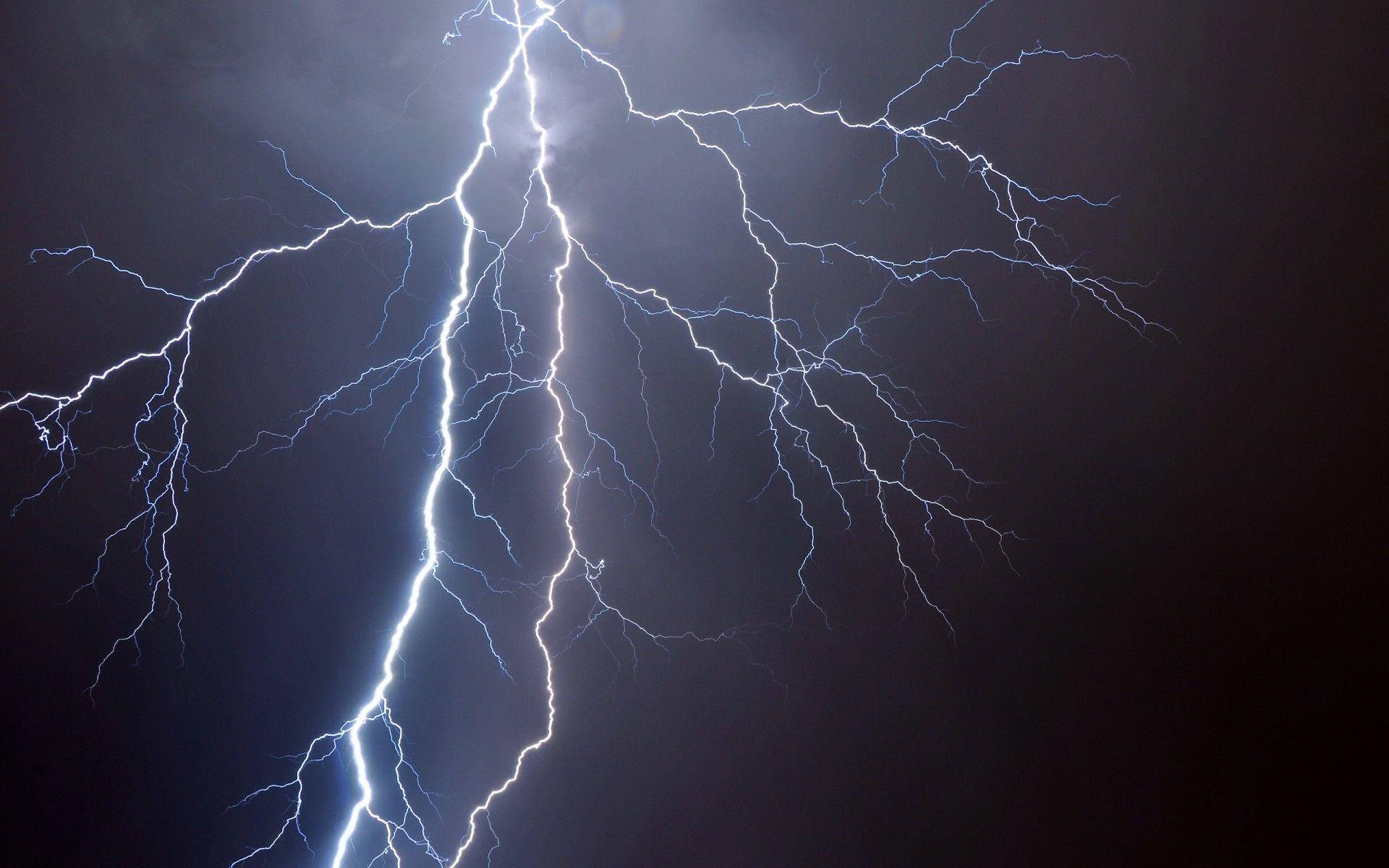 電力 桌布 壁紙 — 一道強大的閃電在黑暗的暴風雨天空中分叉，鋸齒狀的藍白色枝條照亮了雲層。
