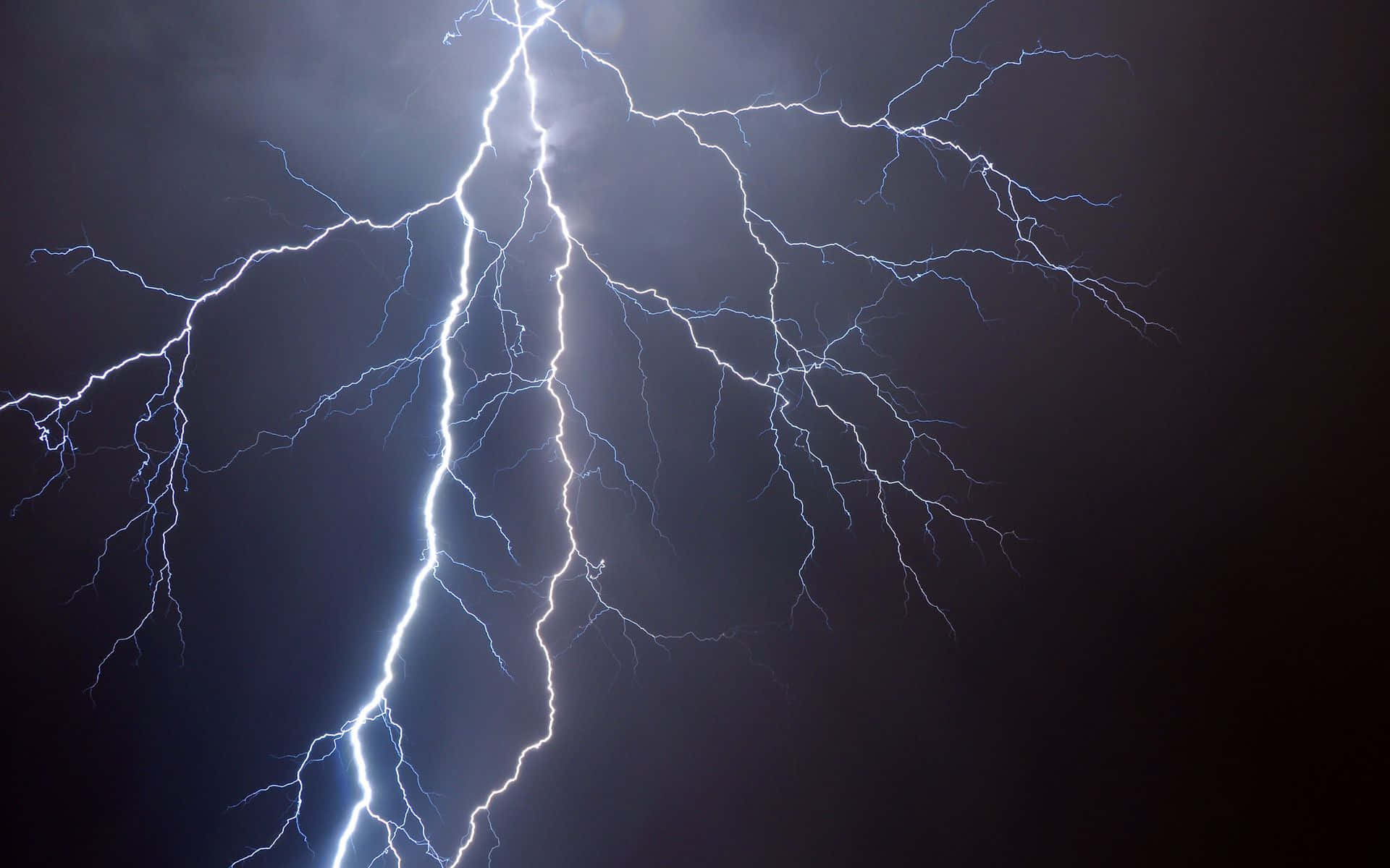 Cool Lightning 桌布 壁紙 — 一道強大的閃電在黑暗的暴風雨天空中分叉，形成戲劇性的自然景觀。