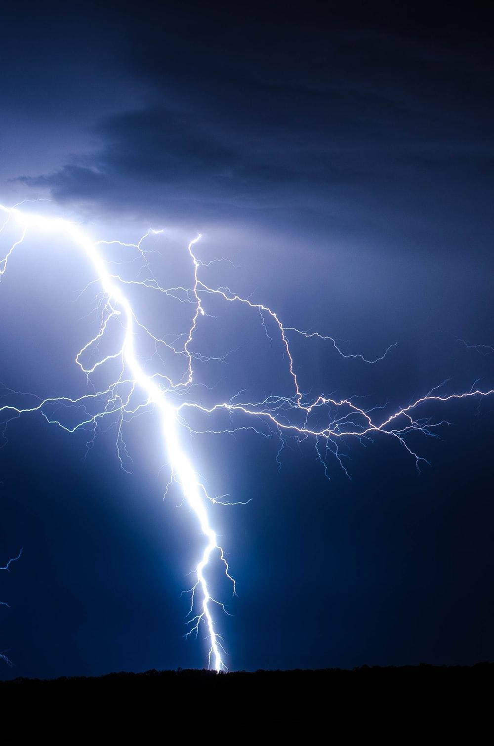 Electricity 桌布 壁紙 — 一道強大的閃電在黑暗的暴風雨天空中分叉，照亮了下面的地平線。