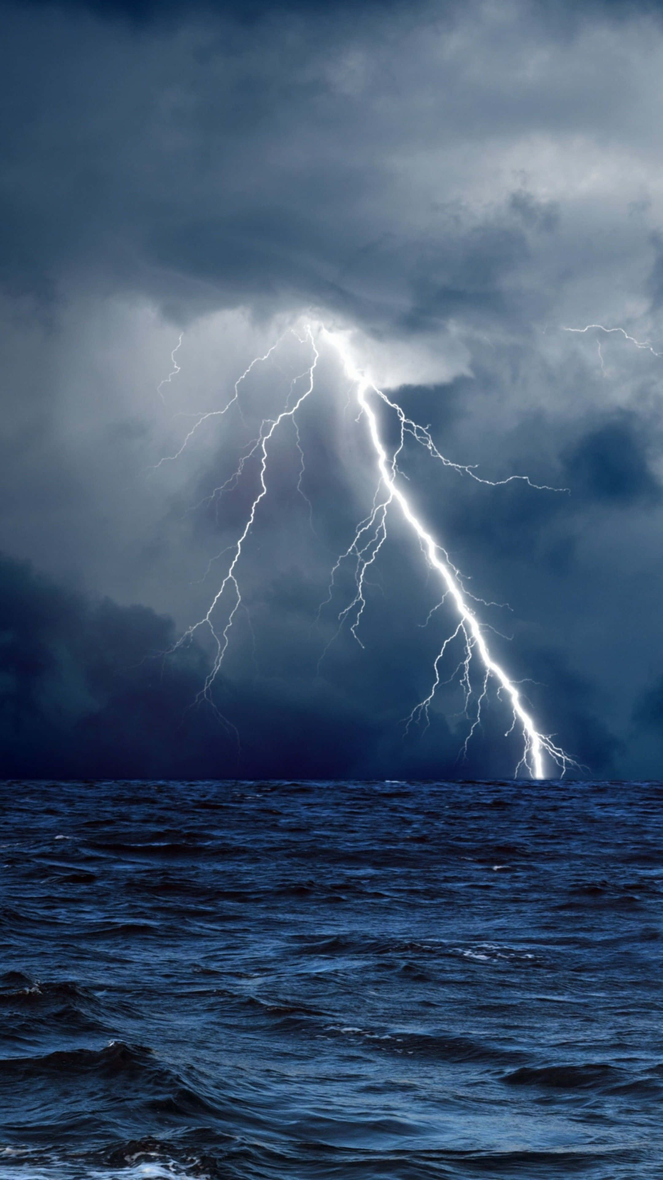 Thunderstorm 桌布 壁紙 — 一道強大的閃電從暴風雲中擊向洶湧的深藍色海洋。