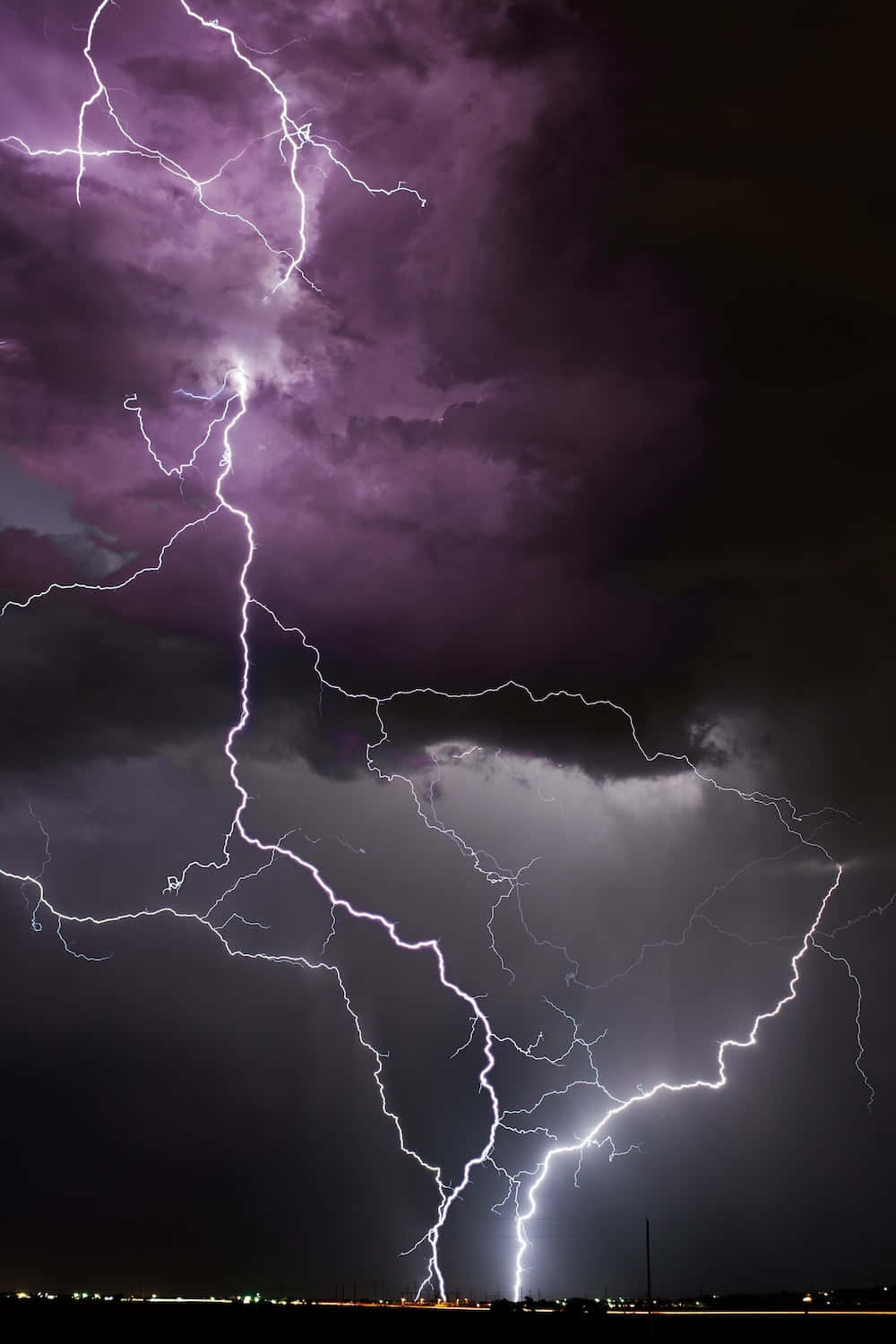 Lightning Bolt 桌布 壁紙 — 一道強烈的紫色和白色閃電劃破戲劇性的夜空，照亮了黑暗的暴風雲。
