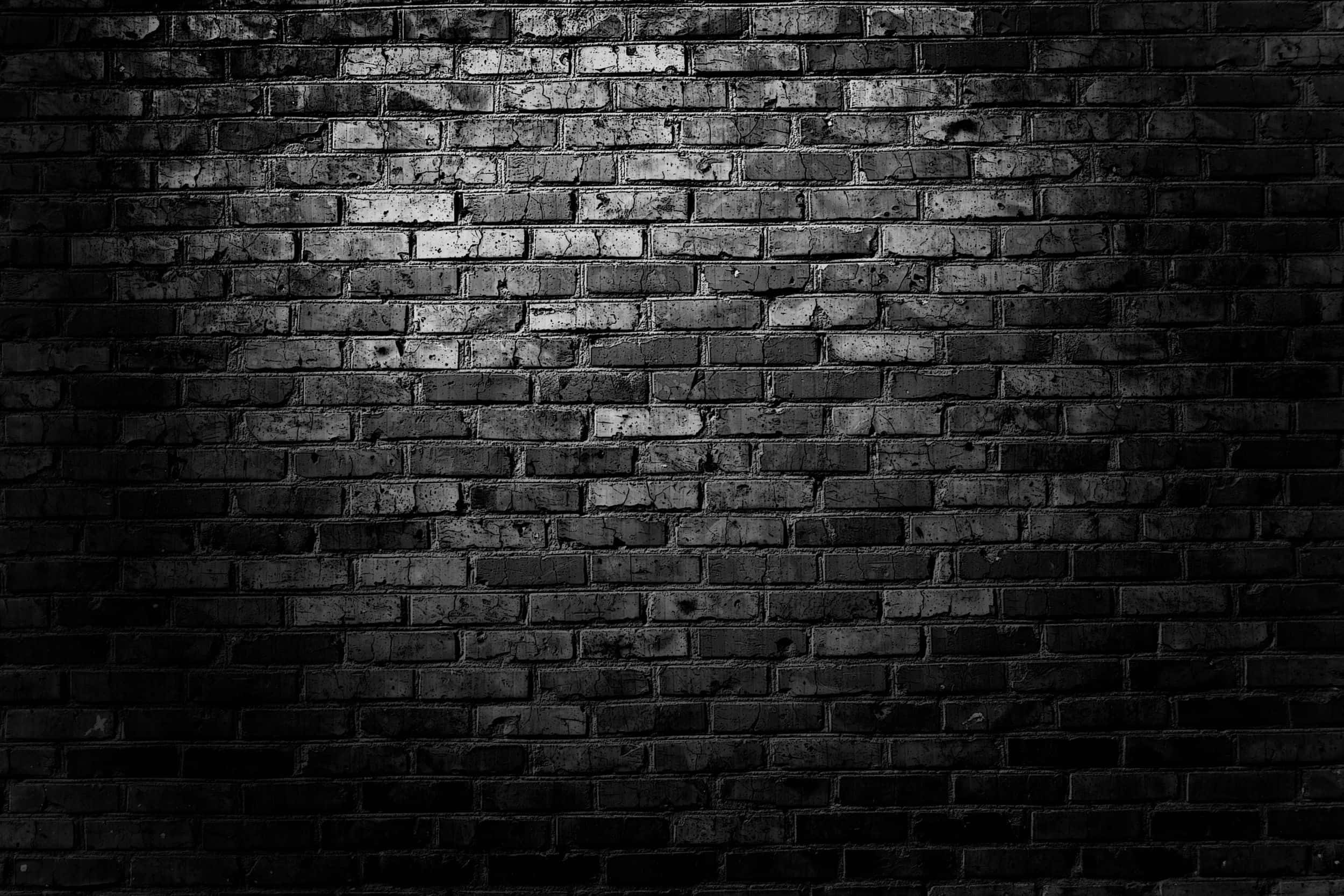Dark Wall 桌布 壁紙 — 一道戲劇性的聚光燈照亮了風化的磚牆，在陰鬱的黑白場景中投下深深的陰影。