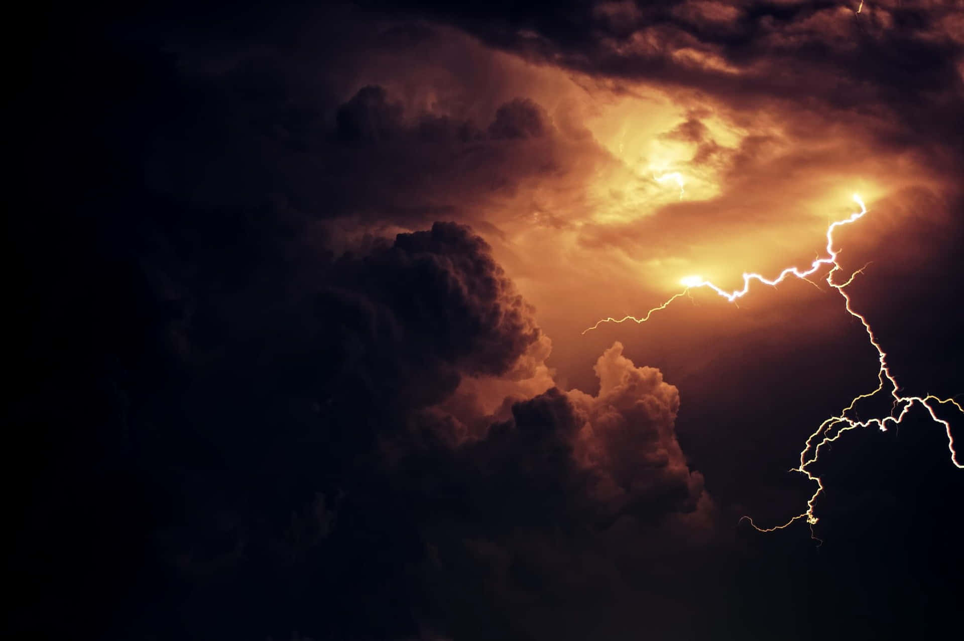 Thunderstorm 桌布 壁紙 — 一道戲劇性的閃電劈開被背後熾熱橙色光照亮的黑暗暴風雲。