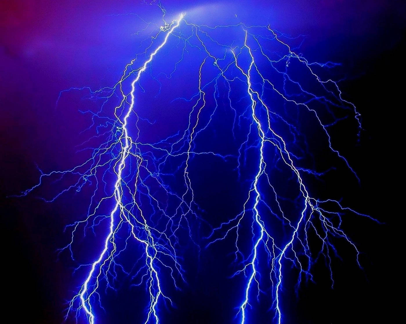 閃電 桌布 壁紙 — 一道戲劇性的電光藍色閃電在深紫色和黑色的暴風雨天空中分叉。