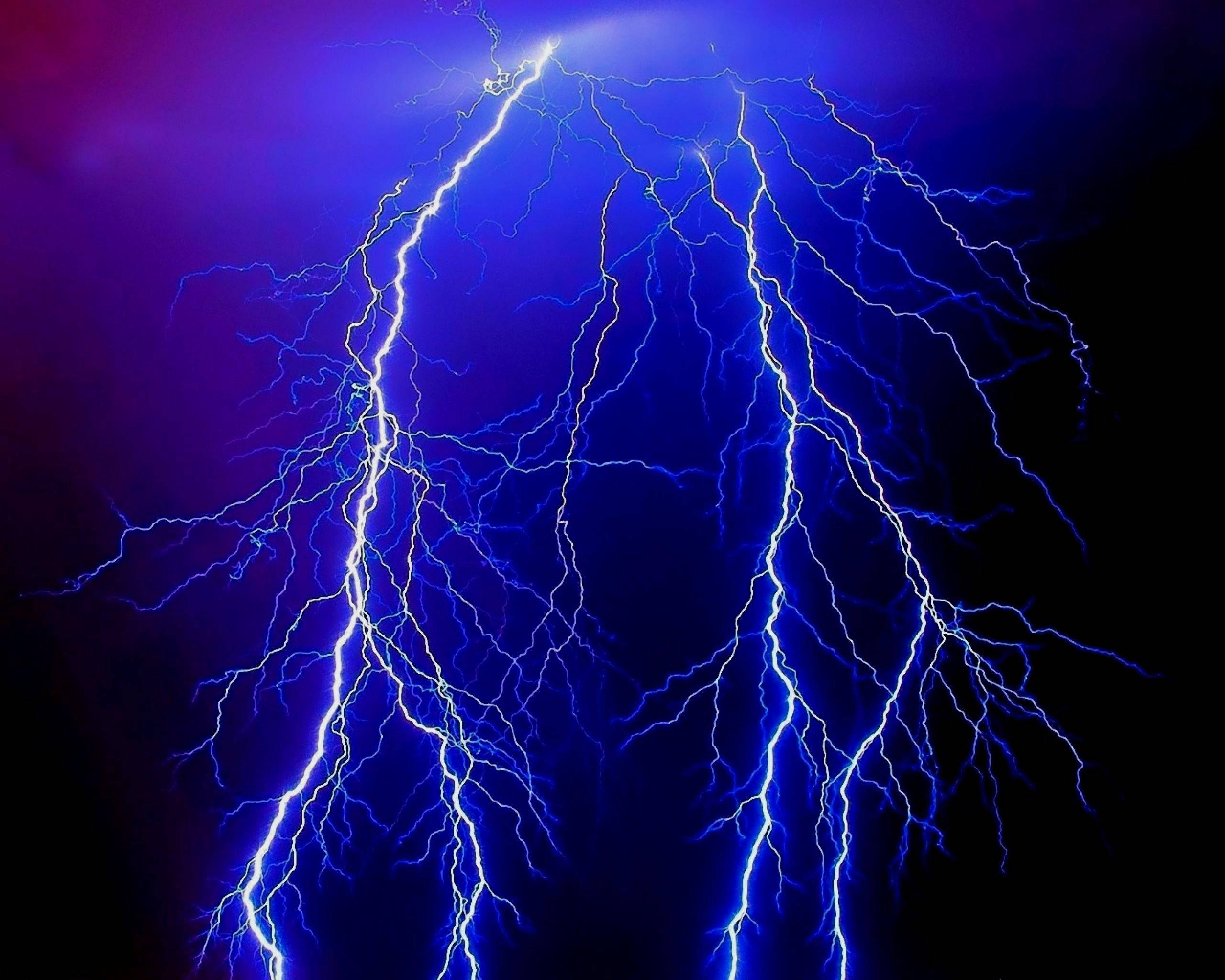 閃電 桌布 壁紙 — 一道戲劇性的電藍色閃電在深紫色和黑色的暴風雨天空中分叉。