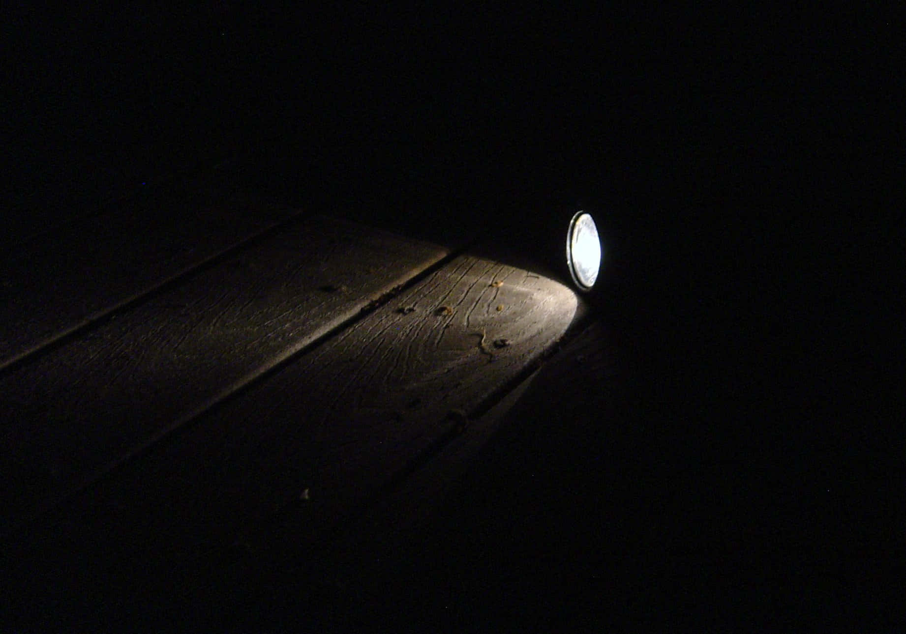 Flashlight 桌布 壁紙 — 一道手電筒光束劃破黑暗，照亮夜間甲板上風化的木板。