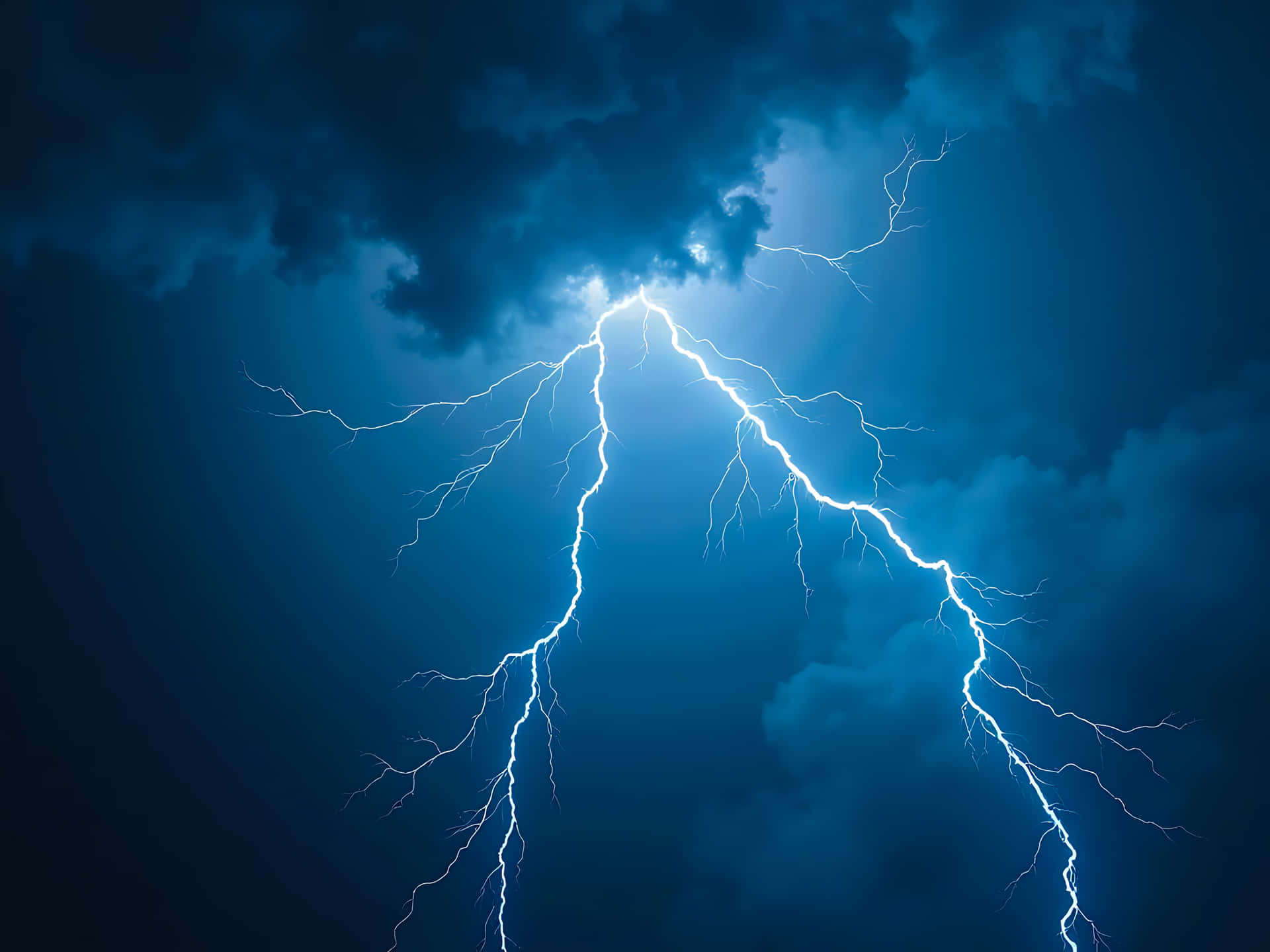 Lightning strikes illuminating a dark and cloudy night sky during a storm 壁紙 — 一道明亮的白色閃電戲劇性地劃過充滿烏雲的深藍色暴風雨天空。