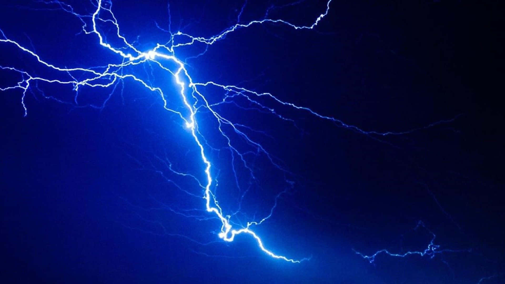 閃電 桌布 壁紙 — 一道明亮的藍色閃電在深靛藍色的夜空中分叉，呈現出戲劇性的自然景象。