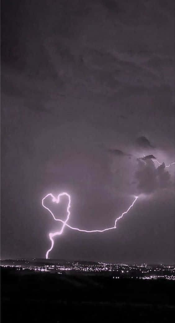 愛心 桌布 壁紙 — 一道明亮的閃電在遠方城市景觀上方的暴風雨夜空中形成心形。