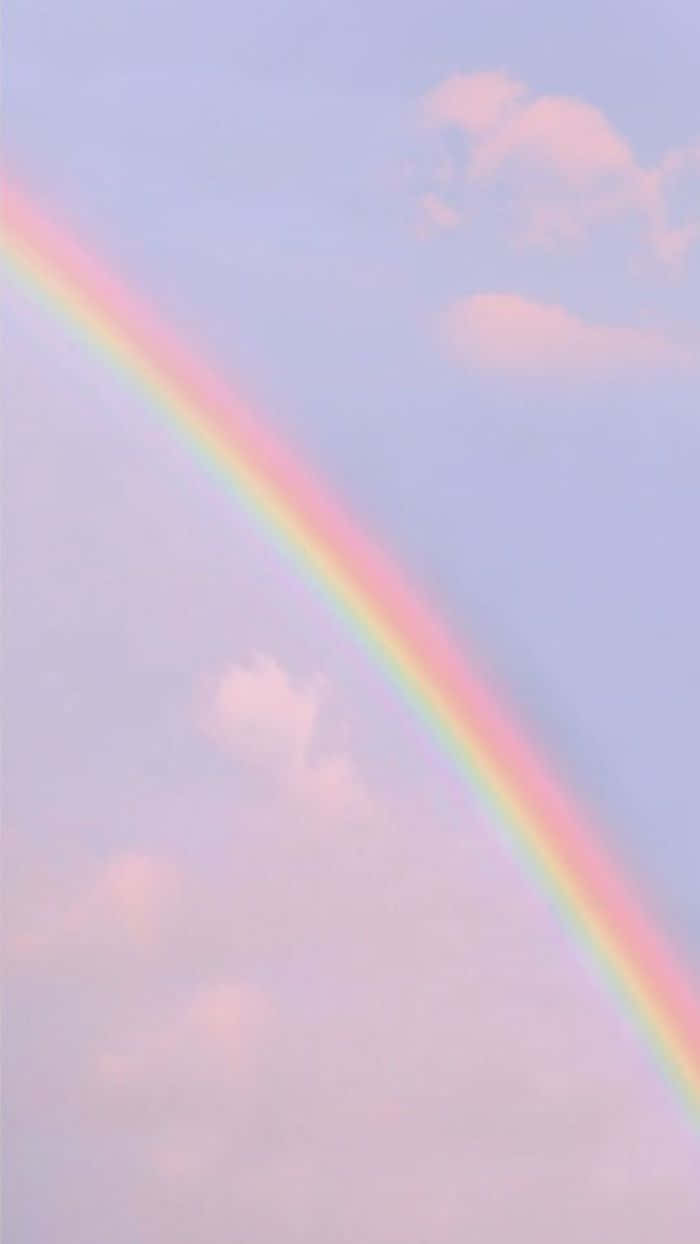Cute Rainbow 桌布 壁紙 — 一道柔和的粉彩彩虹優雅地橫跨在夢幻的薰衣草色天空，點綴著輕柔的粉紅色雲朵。