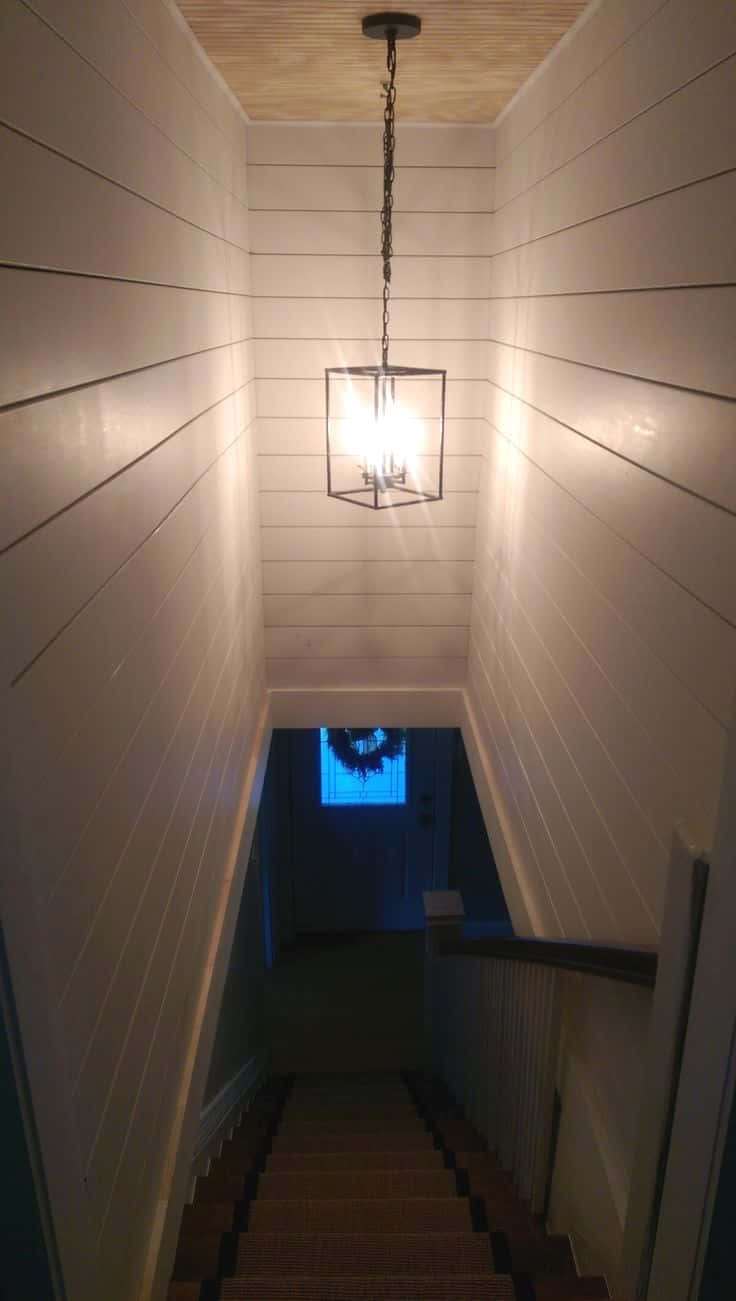 Basement 桌布 壁紙 — 一道溫暖照明的木樓梯，帶有搭接牆壁，向上通往懸掛在木天花板上發光的燈籠。