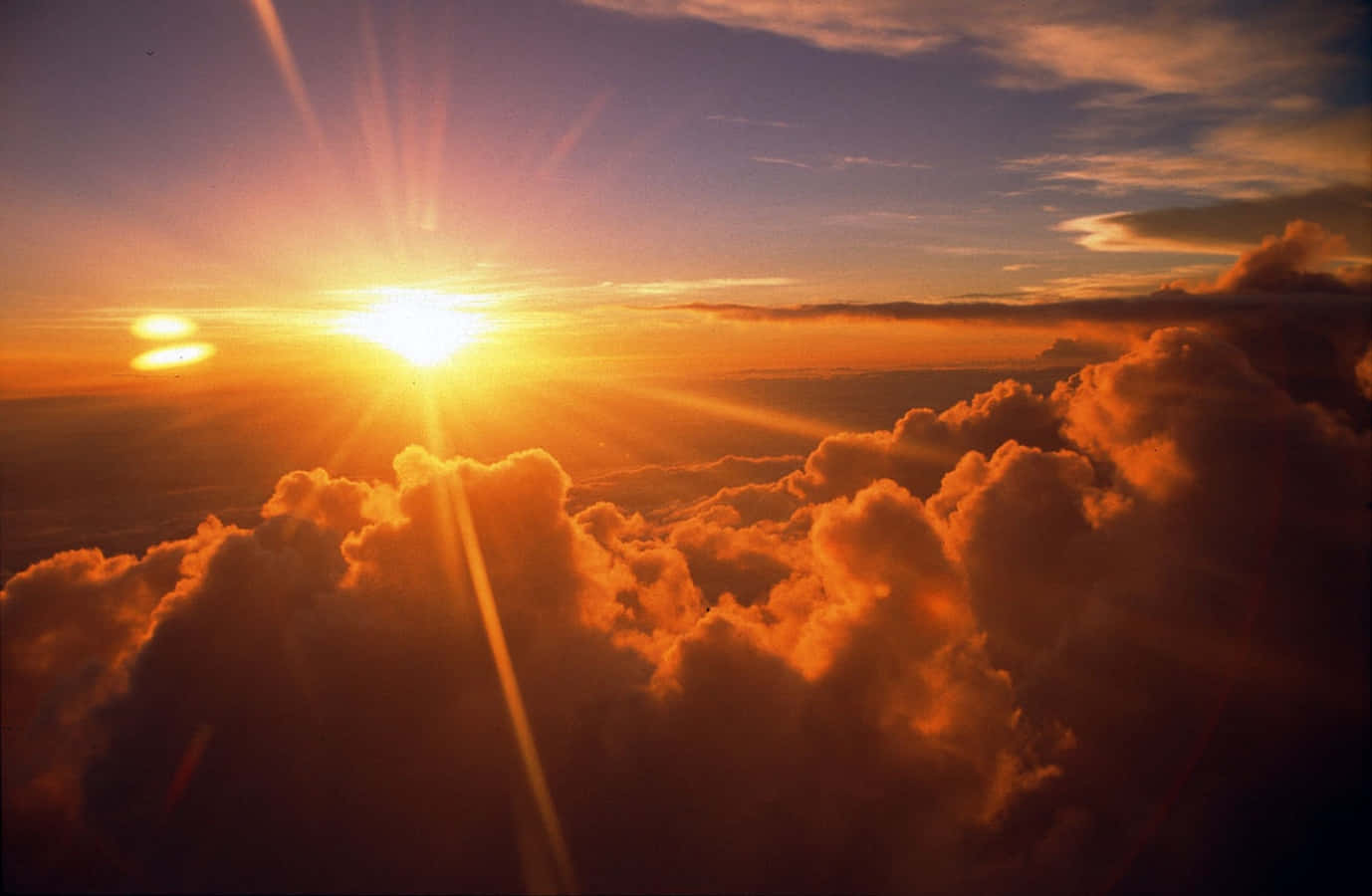 太陽 桌布 壁紙 — 一道燦爛的陽光從上方穿透豐厚的橙色雲層，將金色光線灑向暮色天空。