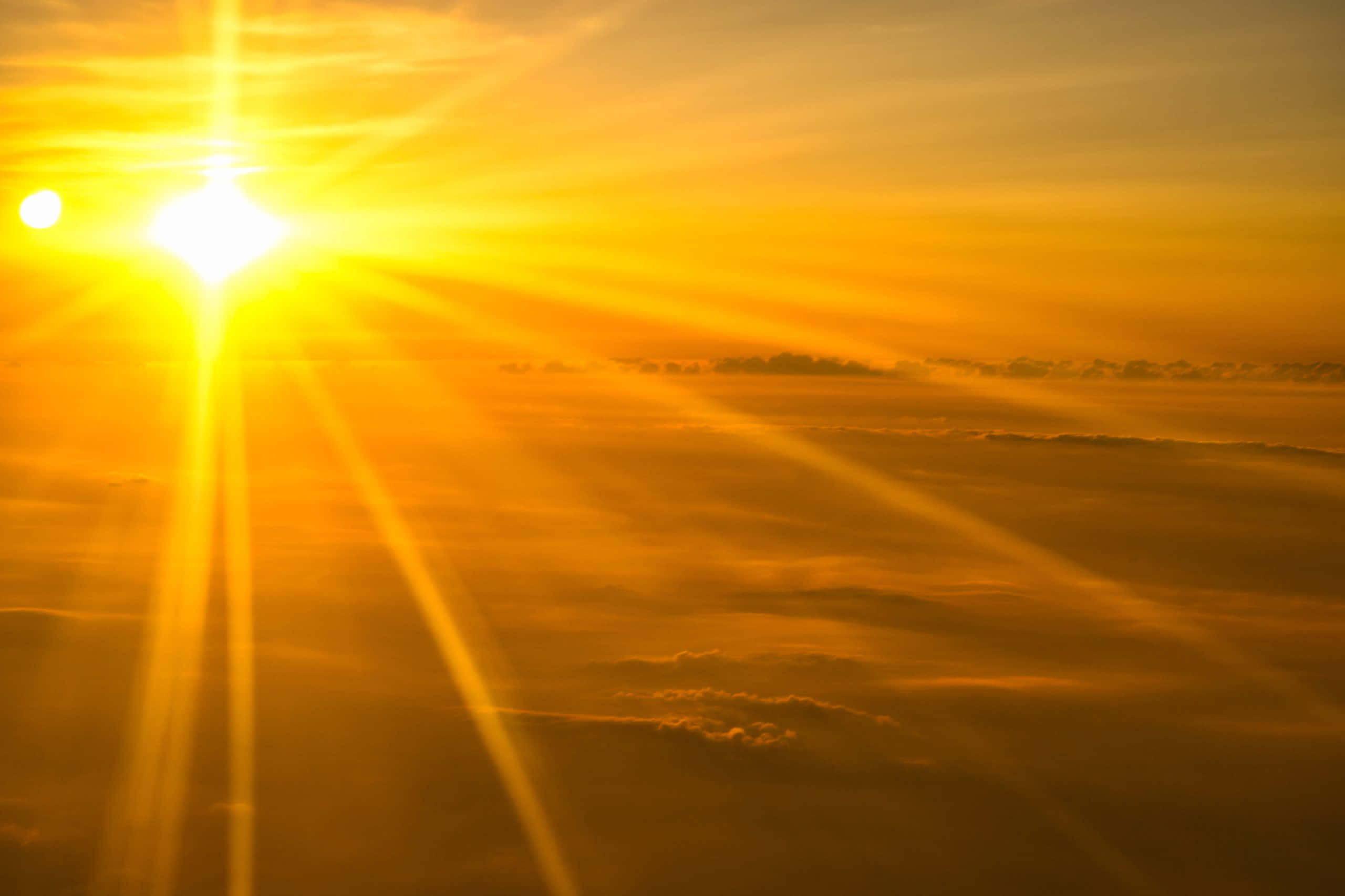 Bright 桌布 壁紙 — 一道燦爛的陽光從上方穿透金色雲層，在迷濛的橙色和黃色海洋上投射出戲劇性的光線。