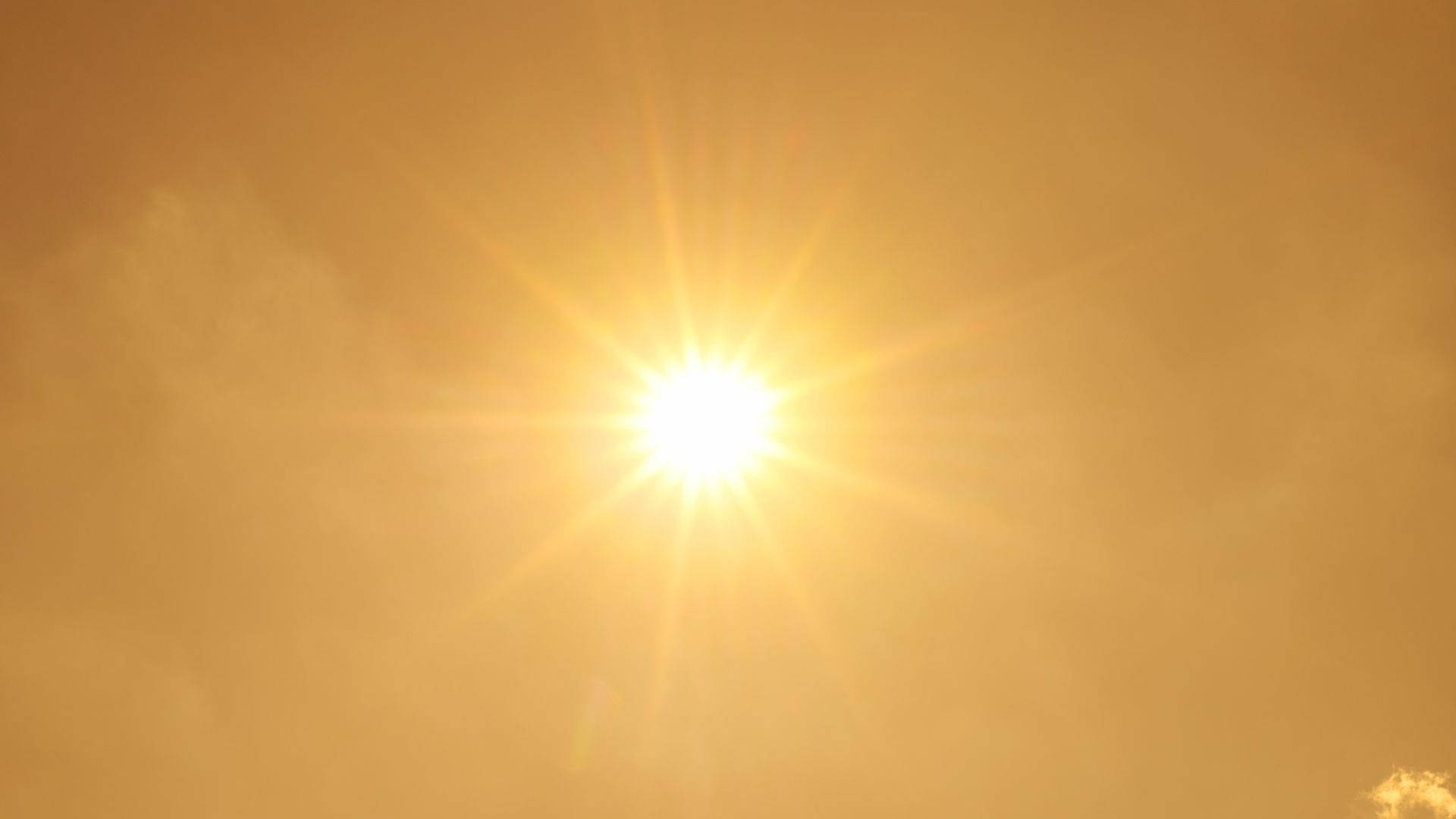 太陽 桌布 壁紙 — 一道燦爛的陽光穿透朦朧的琥珀色雲層，在天空中投射出耀眼的星芒。