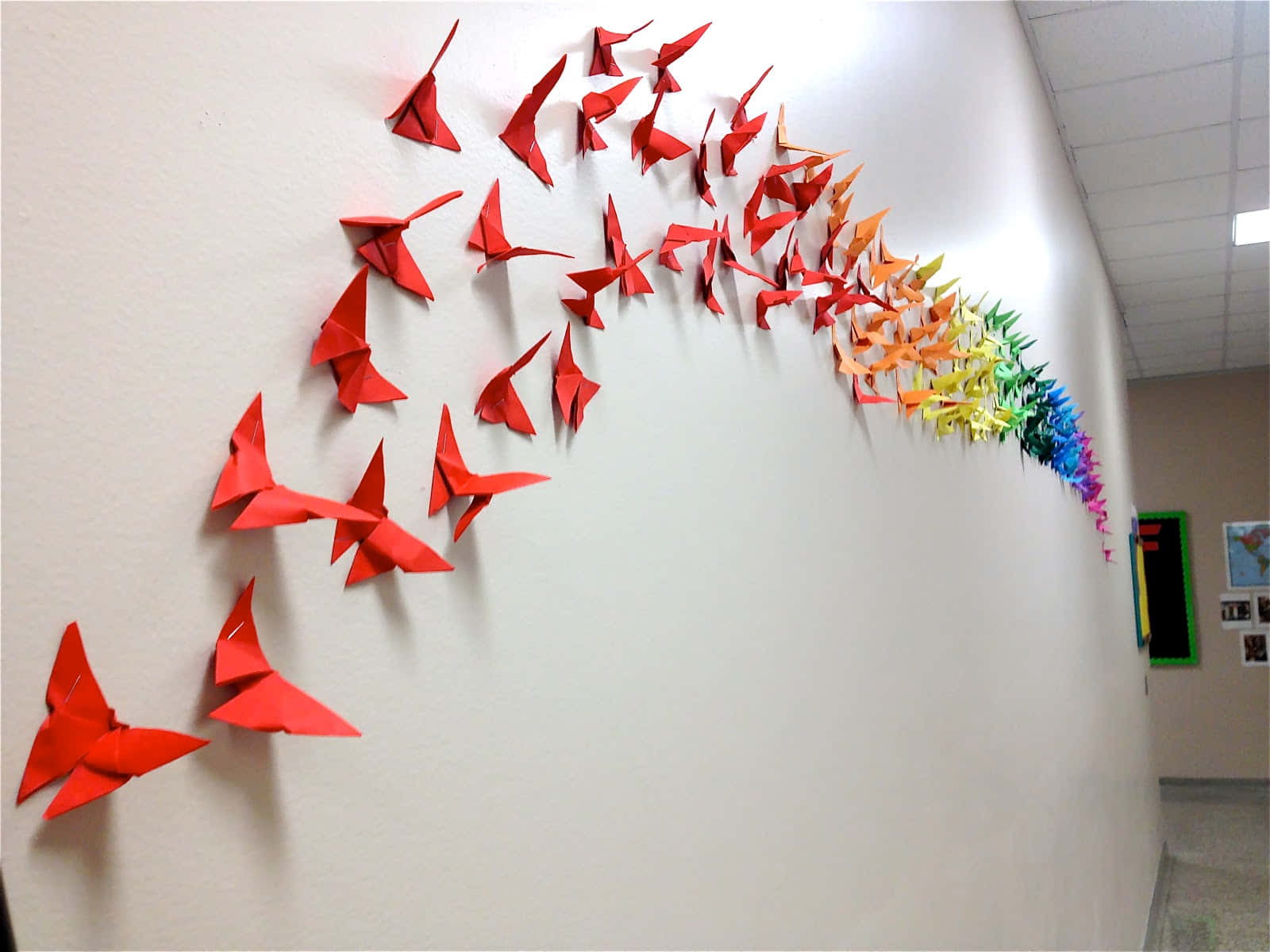 Butterfly Origami 桌布 壁紙 — 一道由紙鶴組成的鮮豔彩虹，裝飾著從紅色漸變到紫色的弧形走廊牆壁。