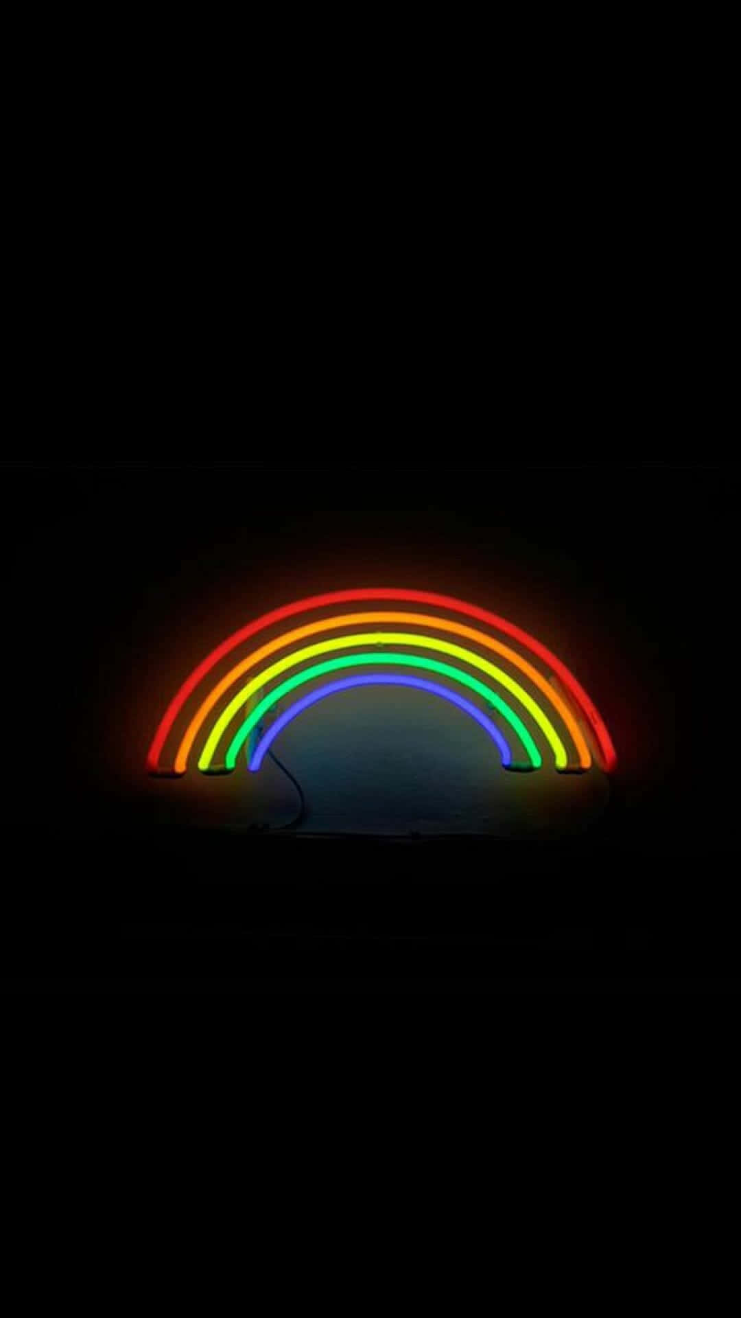 Rainbow iPhone 桌布 壁紙 — 一道發光的霓虹彩虹在漆黑的背景上明亮地拱起，投射出柔和的有色光線。