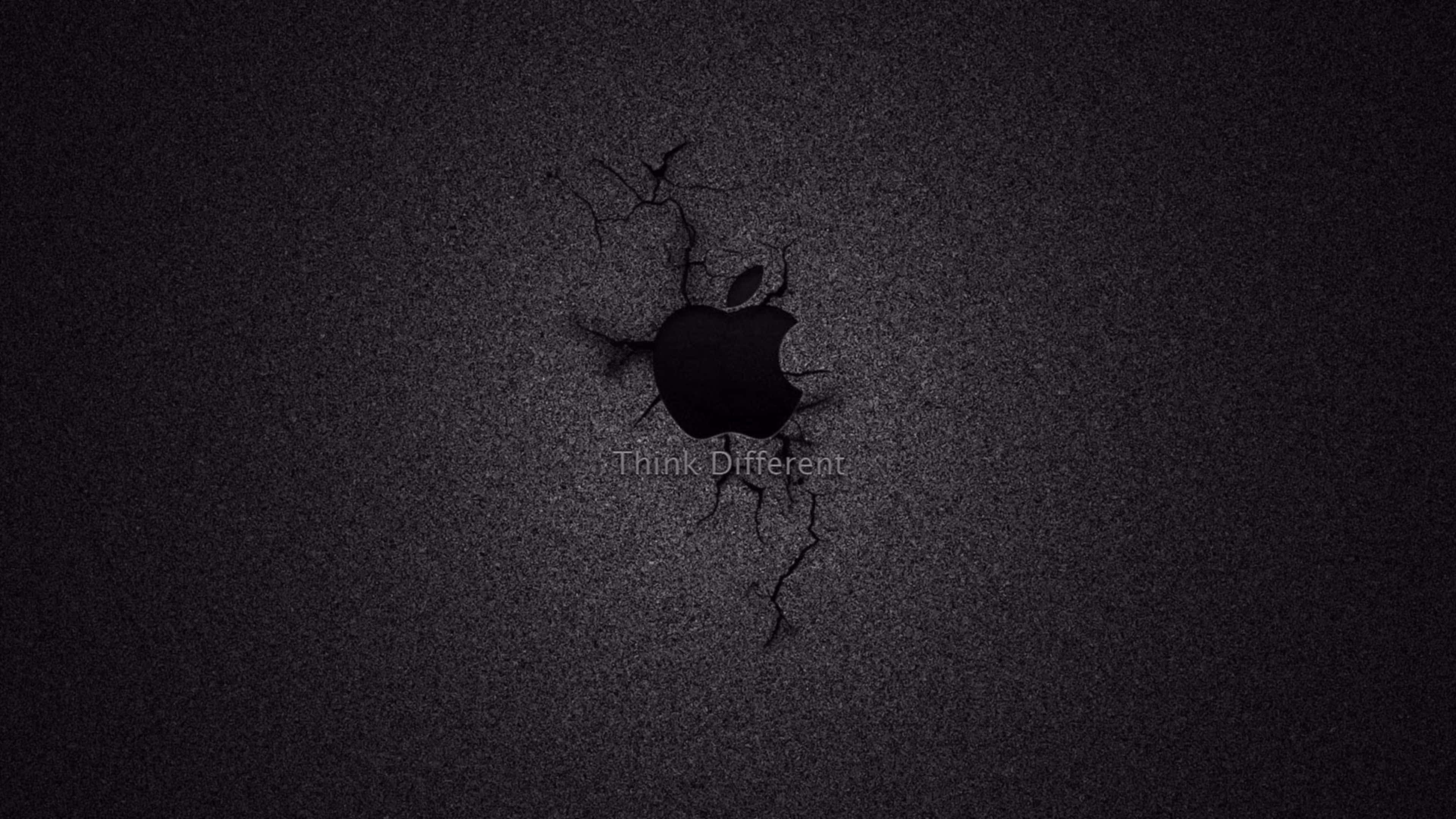 4K Apple 桌布 壁紙 — 一道破裂的黑色牆壁露出發光的Apple標誌，下方有Think Different文字。