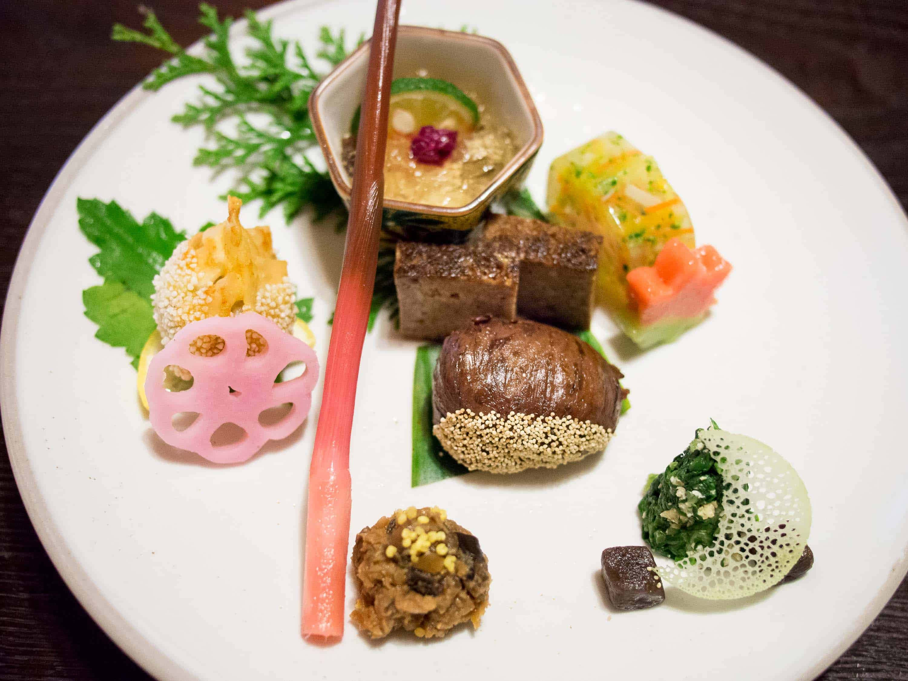 Tokyo Japan 桌布 壁紙 — 一道精心擺盤的美食，在白色陶瓷盤上呈現色彩繽紛的前菜和裝飾。