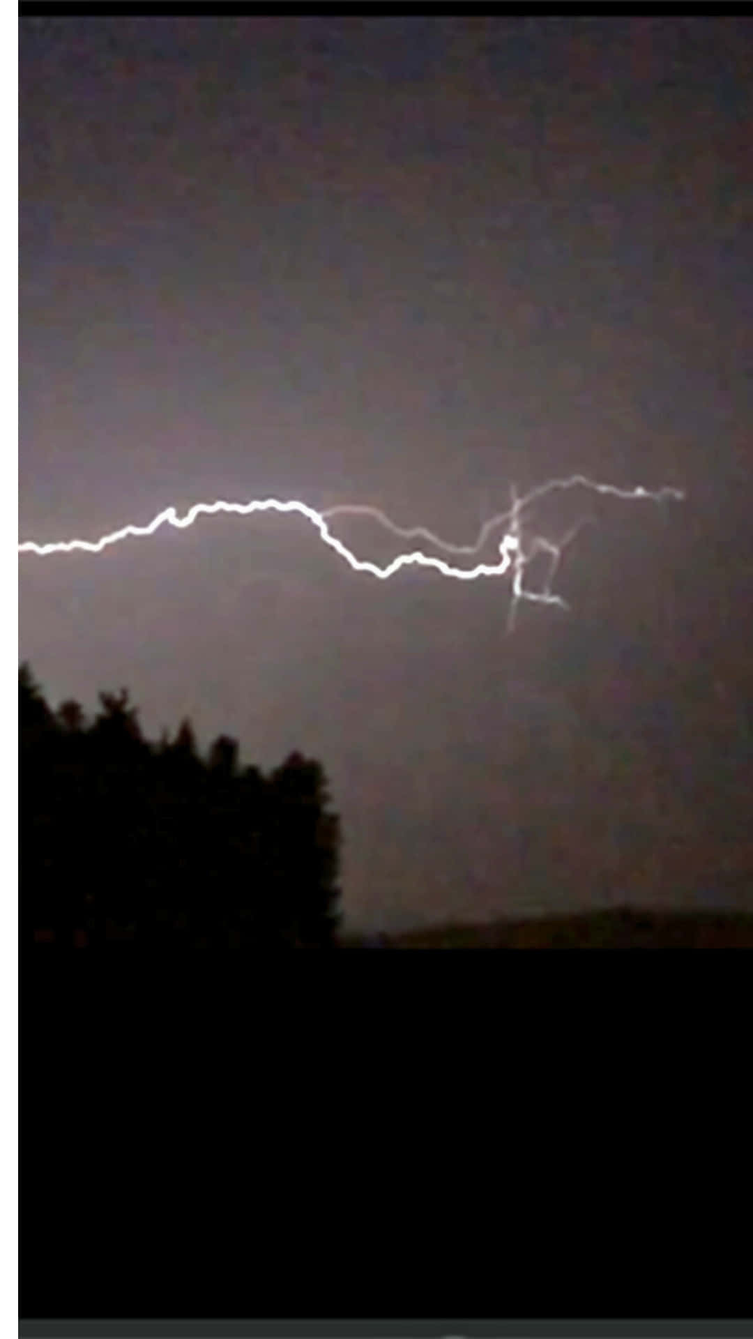 dark lighting 壁紙 — 一道鋸齒狀的白色閃電在樹木剪影上方黑暗的暴風雨天空中分叉。