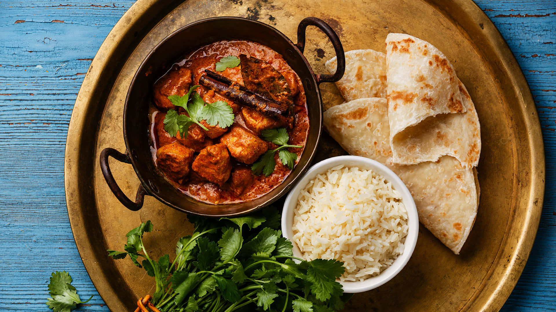 Indian 桌布 壁紙 — 一道香料豐富的咖哩，配以豆腐和香菜，盛在銅鍋中，與米飯和印度烤餅一起放在質樸的藍色木桌上。