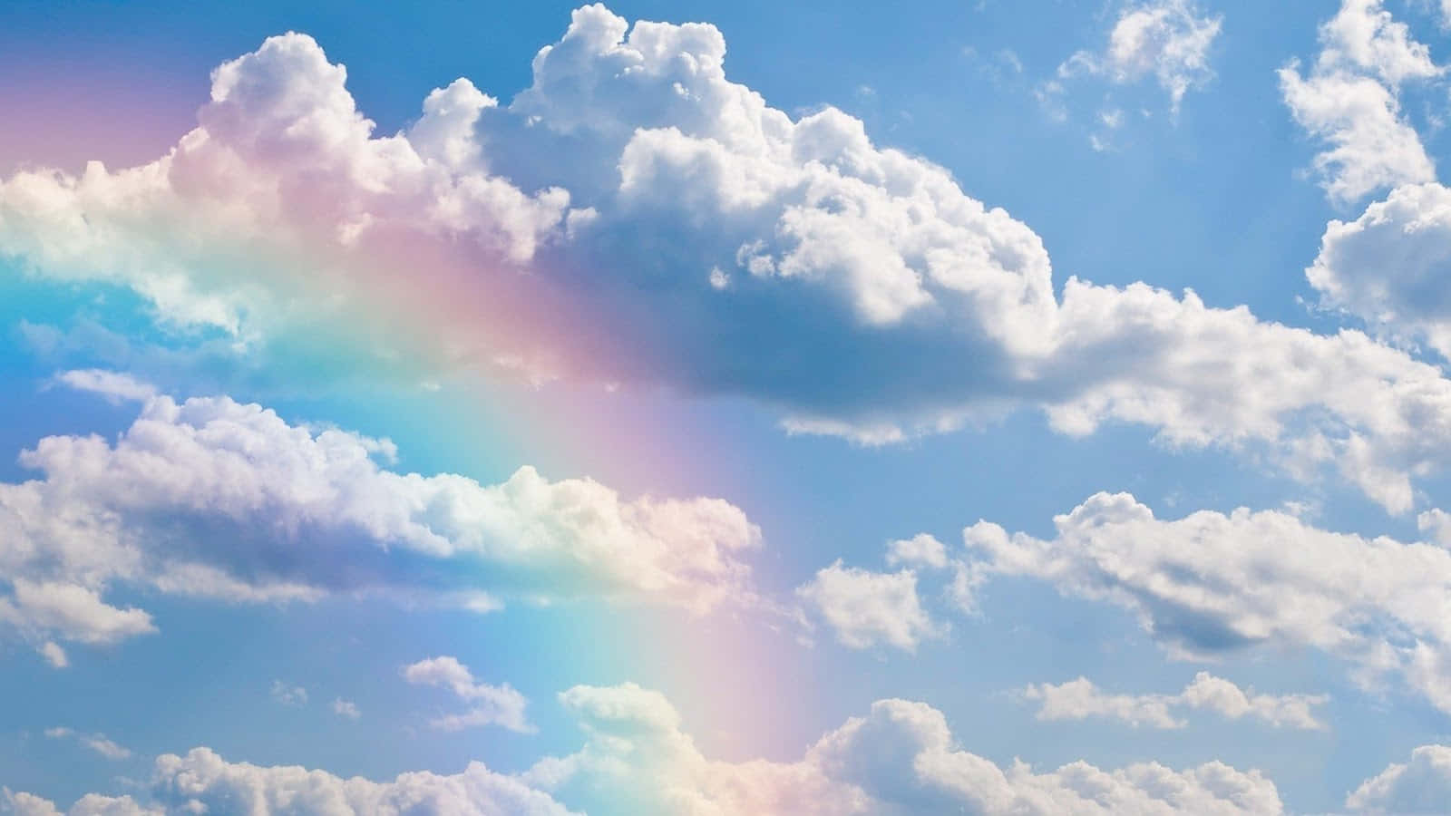 雲朵 桌布 壁紙 — 一道鮮豔的彩虹優雅地穿過蓬鬆的白雲，映襯著明亮的藍天。