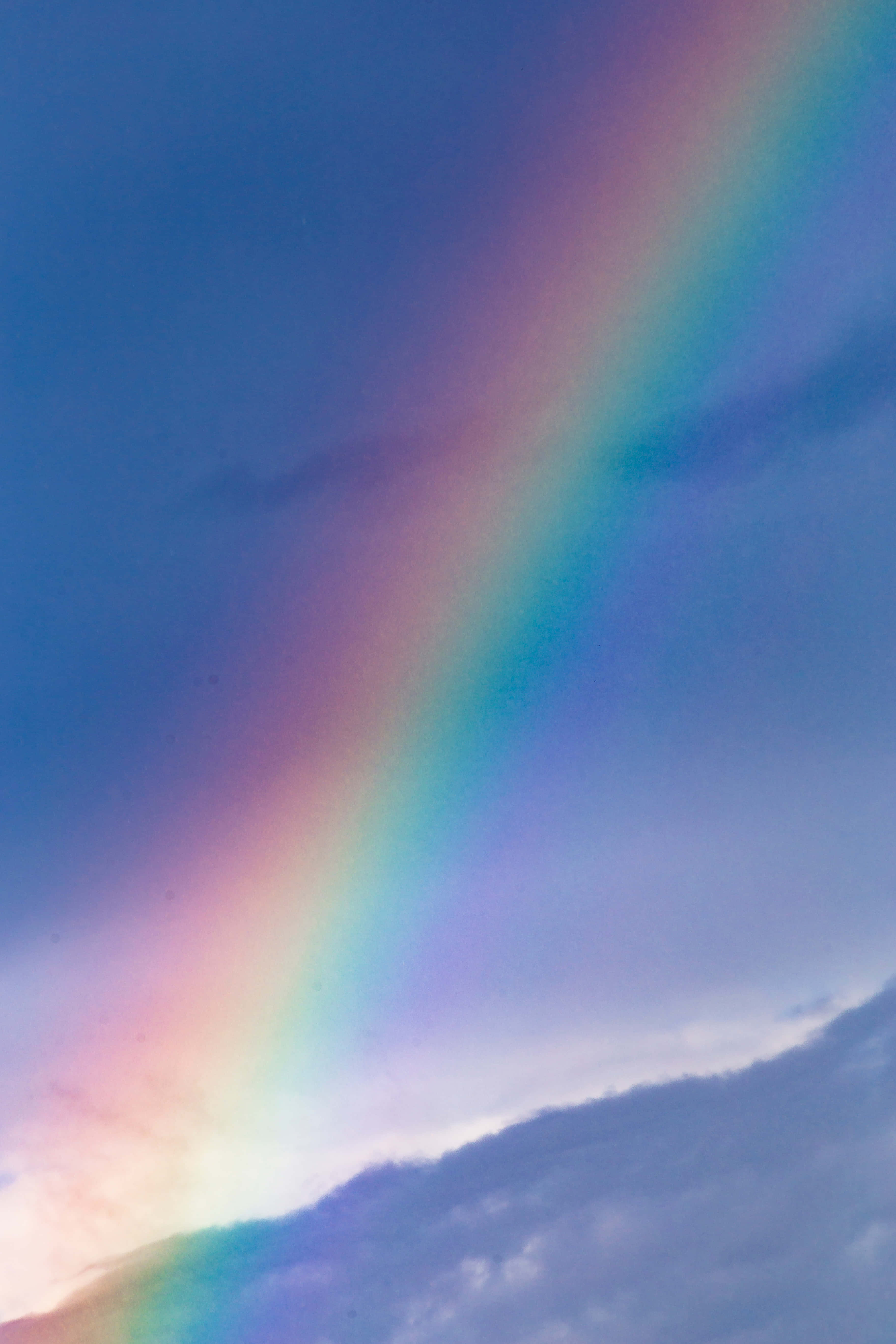 Cute Rainbow 桌布 壁紙 — 一道鮮豔的彩虹橫跨暮色天空，伴隨著柔軟的雲朵和深邃的藍色調。