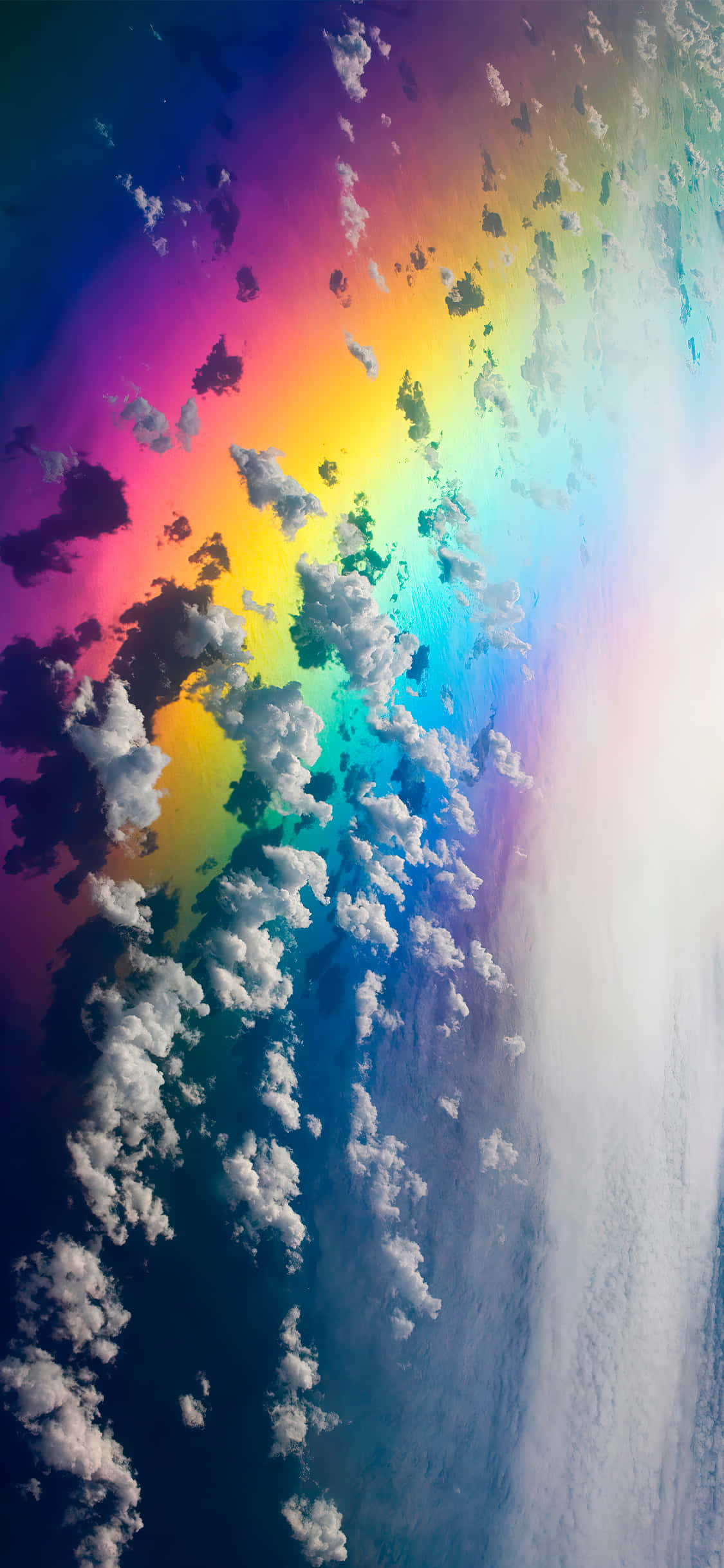 Aesthetic Sky 桌布 壁紙 — 一道鮮豔的彩虹穿過蓬鬆的白雲，映襯著深藍色的天空，右側有一道明亮的陽光。