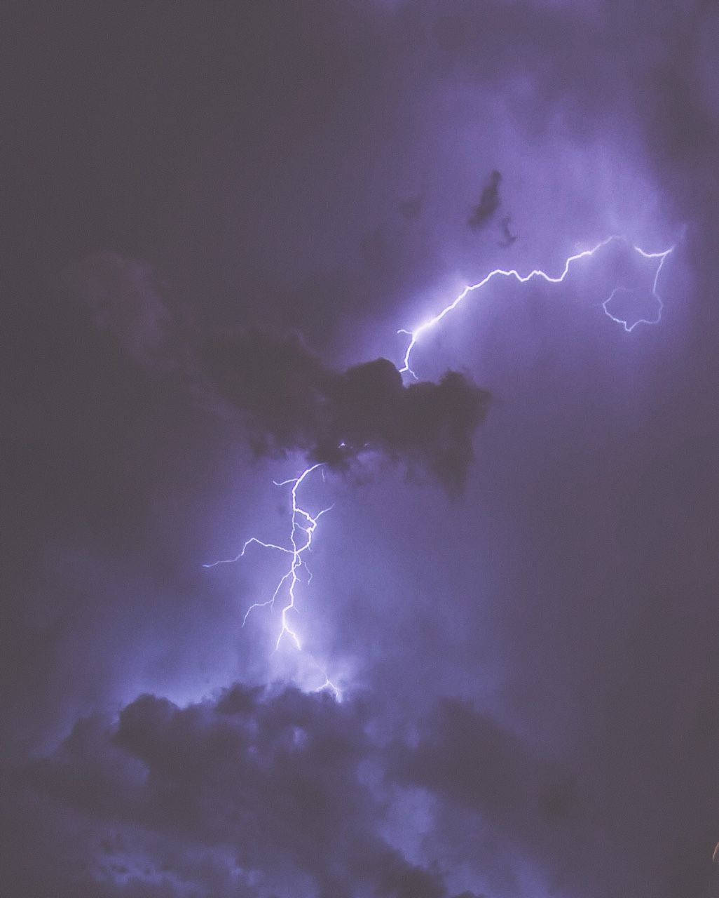 Aesthetic Lightning 桌布 壁紙 — 一道鮮豔的紫色閃電在戲劇性的夜空中穿過黑暗的暴風雲。