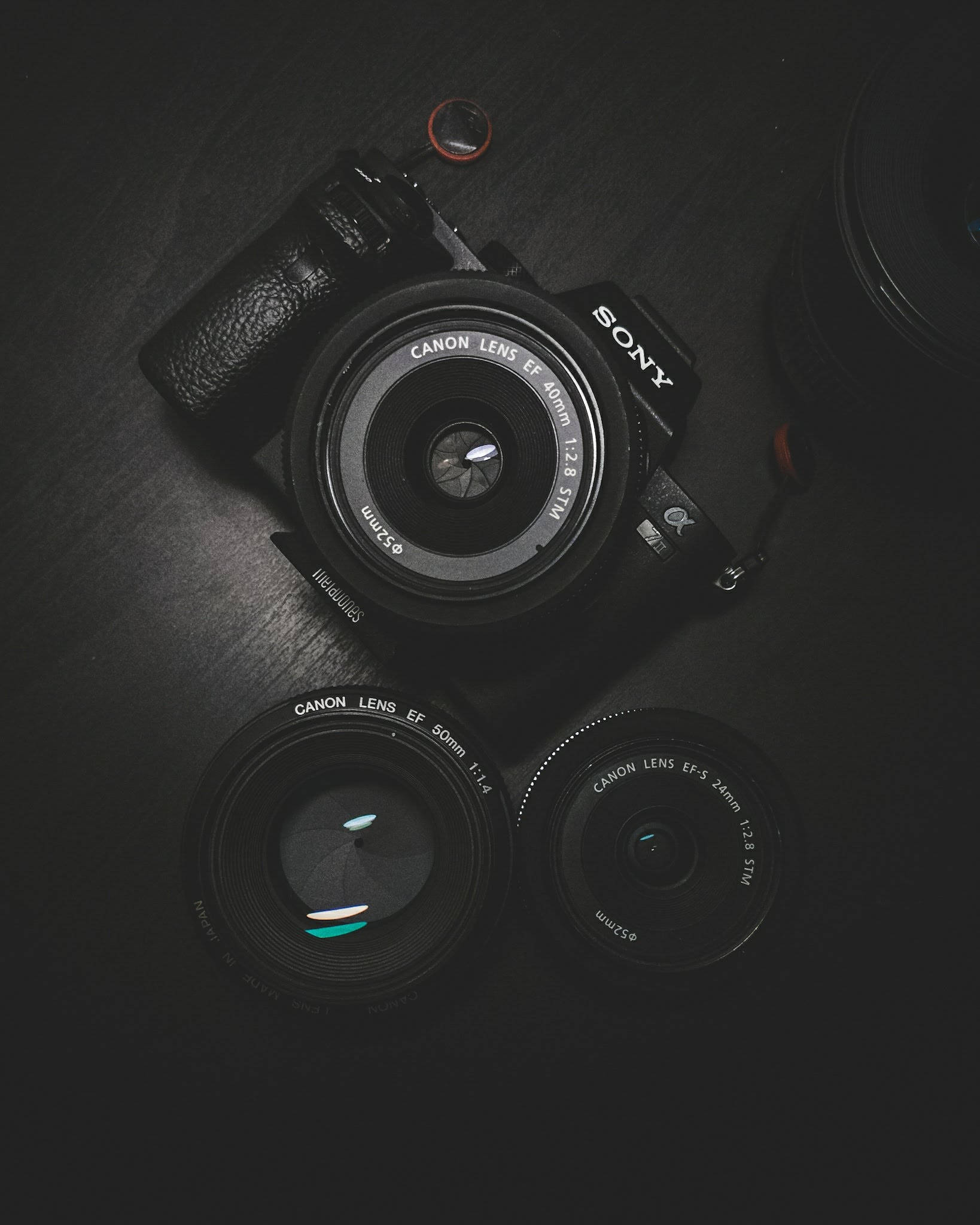 相機 桌布 壁紙 — 一部 Sony 相機配備 Canon 鏡頭，放置在深色木質表面上，燈光營造氛圍。