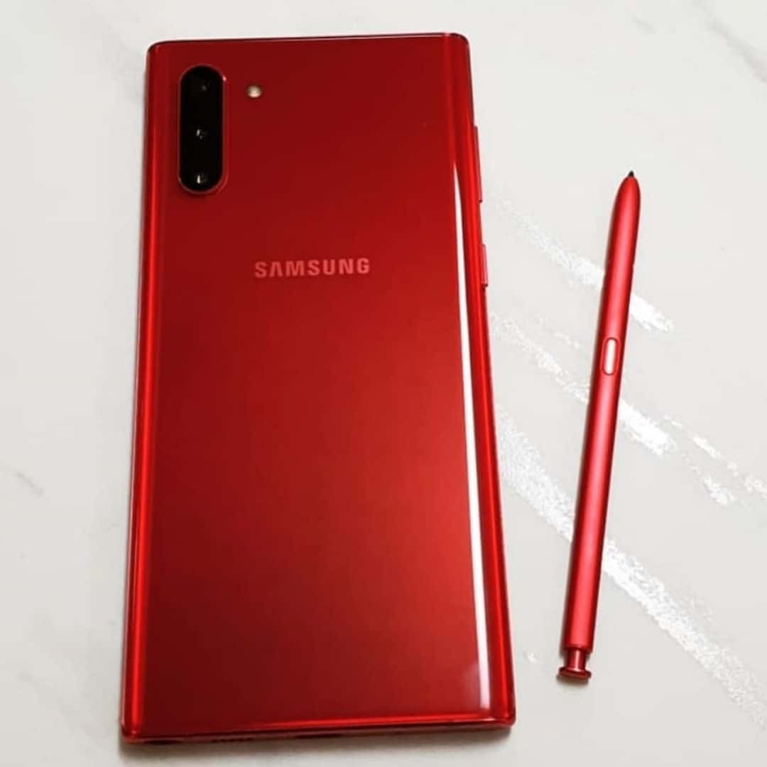Note 10 桌布 壁紙 — 一部亮紅色的Samsung智慧型手機及其匹配的觸控筆放在白色大理石表面上。