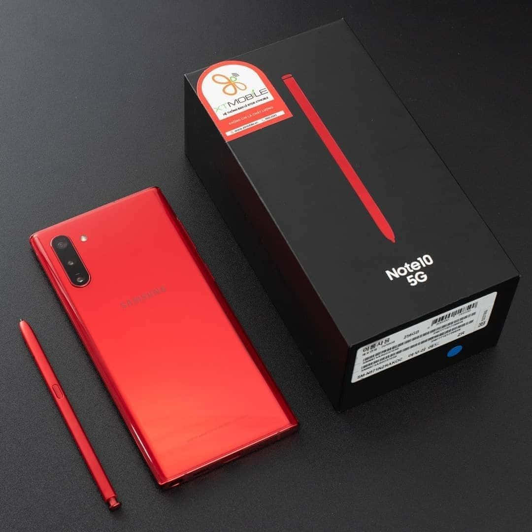 Note 10 桌布 壁紙 — 一部亮面紅色Samsung Note10 5G智慧型手機及其黑色盒子連紅色S Pen放在深色紋理表面上。