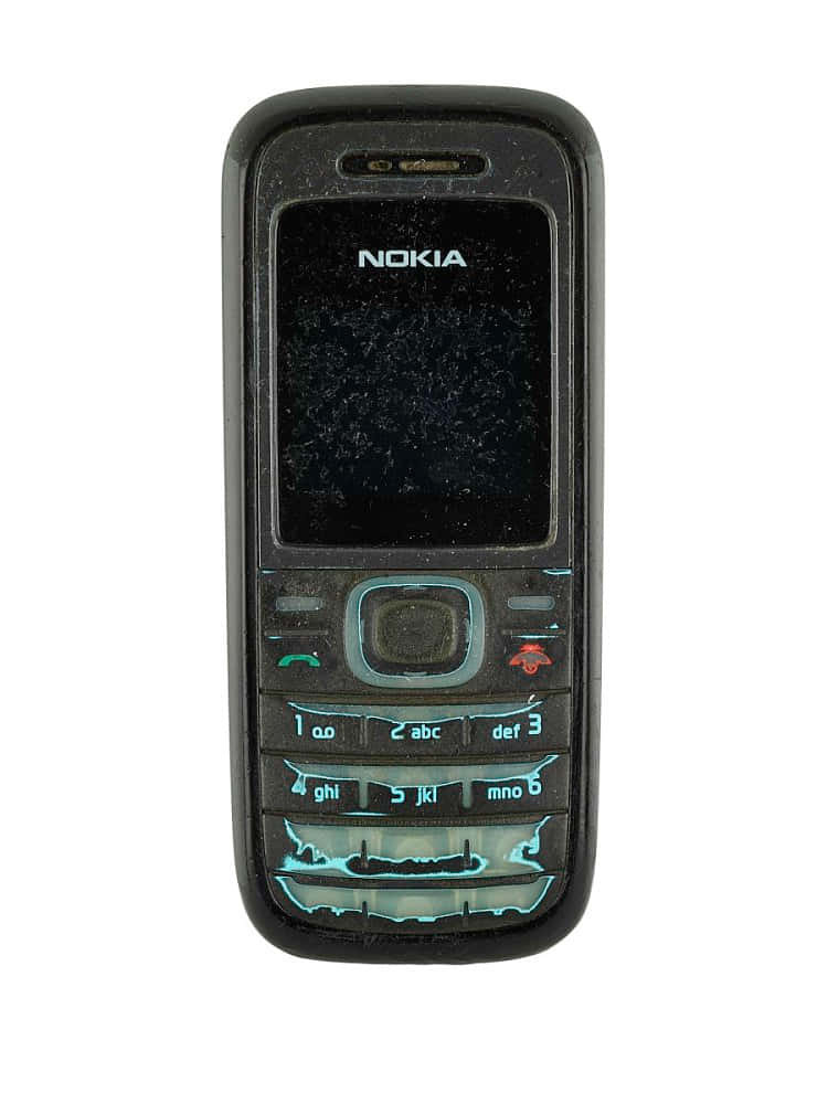 諾基亞 桌布 壁紙 — 一部使用痕跡明顯的黑色 Nokia 手機，螢幕破裂，藍色鍵盤按鍵發光，背景為白色。