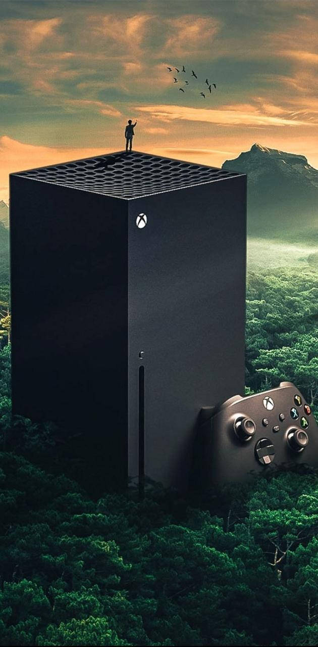 X 桌布 壁紙 — 一部巨大的Xbox主機從森林中升起，旁邊有一個控制器，一個孤獨的身影站在其屋頂上，背景是夕陽天空。