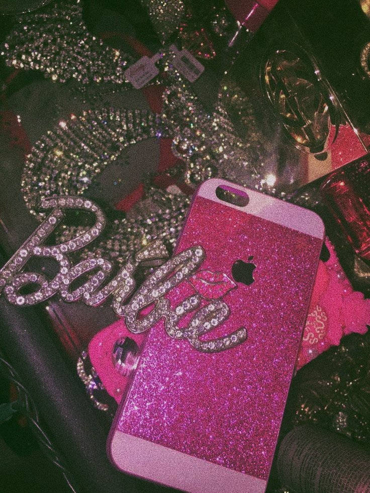 一部帶有水鑽Barbie標誌的粉紅色閃亮iPhone，被閃閃發光的配件包圍。 — 芭比 GIF 壁紙