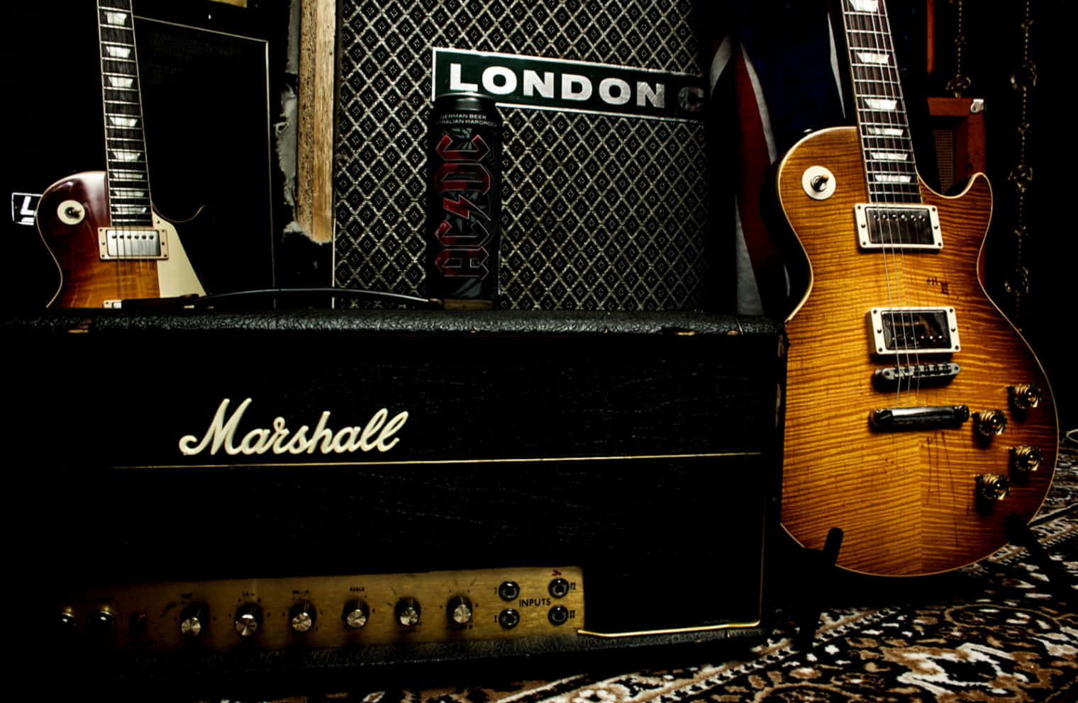 Guitar Aesthetic 桌布 壁紙 — 一部復古 Marshall 擴音器和兩支電吉他放在一個光線昏暗的音樂工作室的圖案地毯上。
