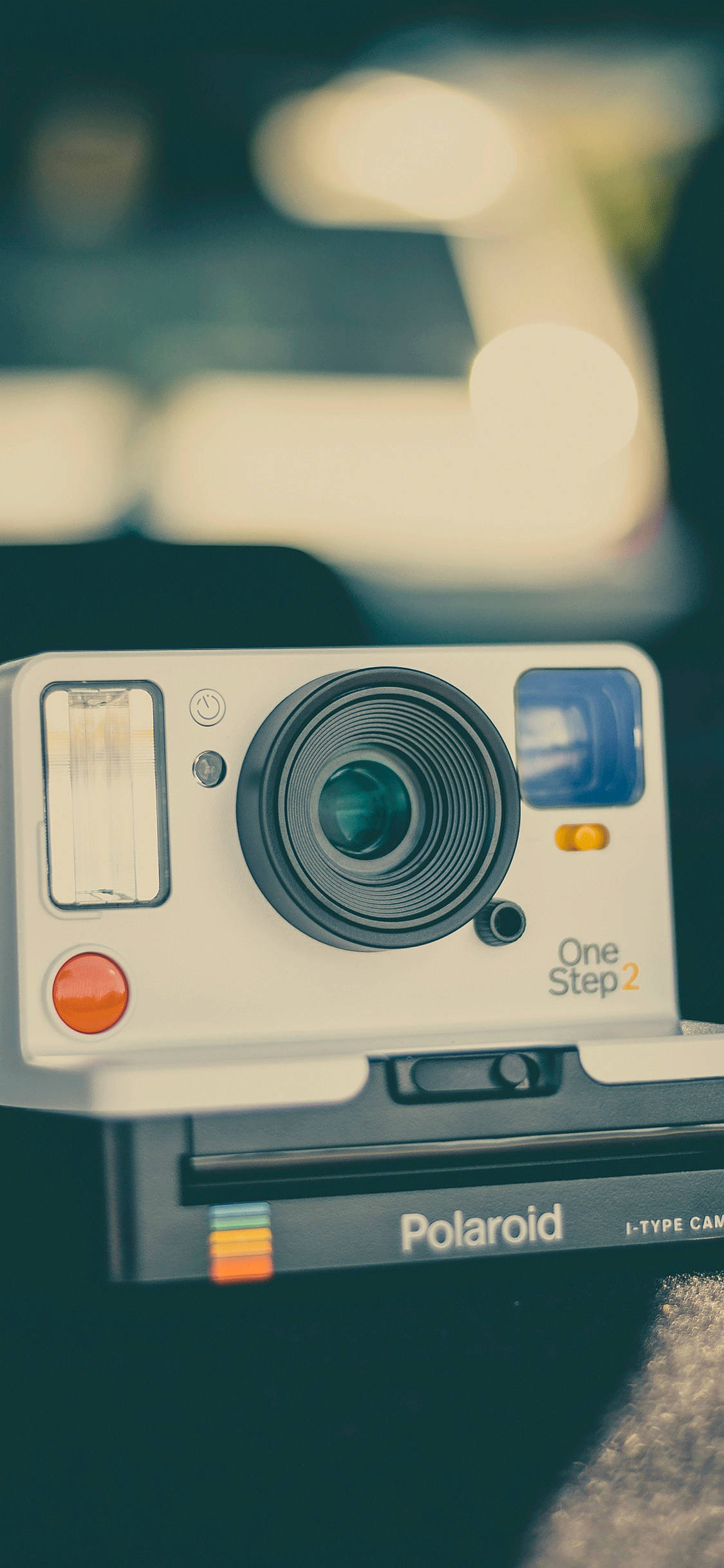 retro aesthetic iPhone 桌布 壁紙 — 一部復古Polaroid One Step 2相機在溫暖散景燈光柔和模糊的背景上清晰對焦。