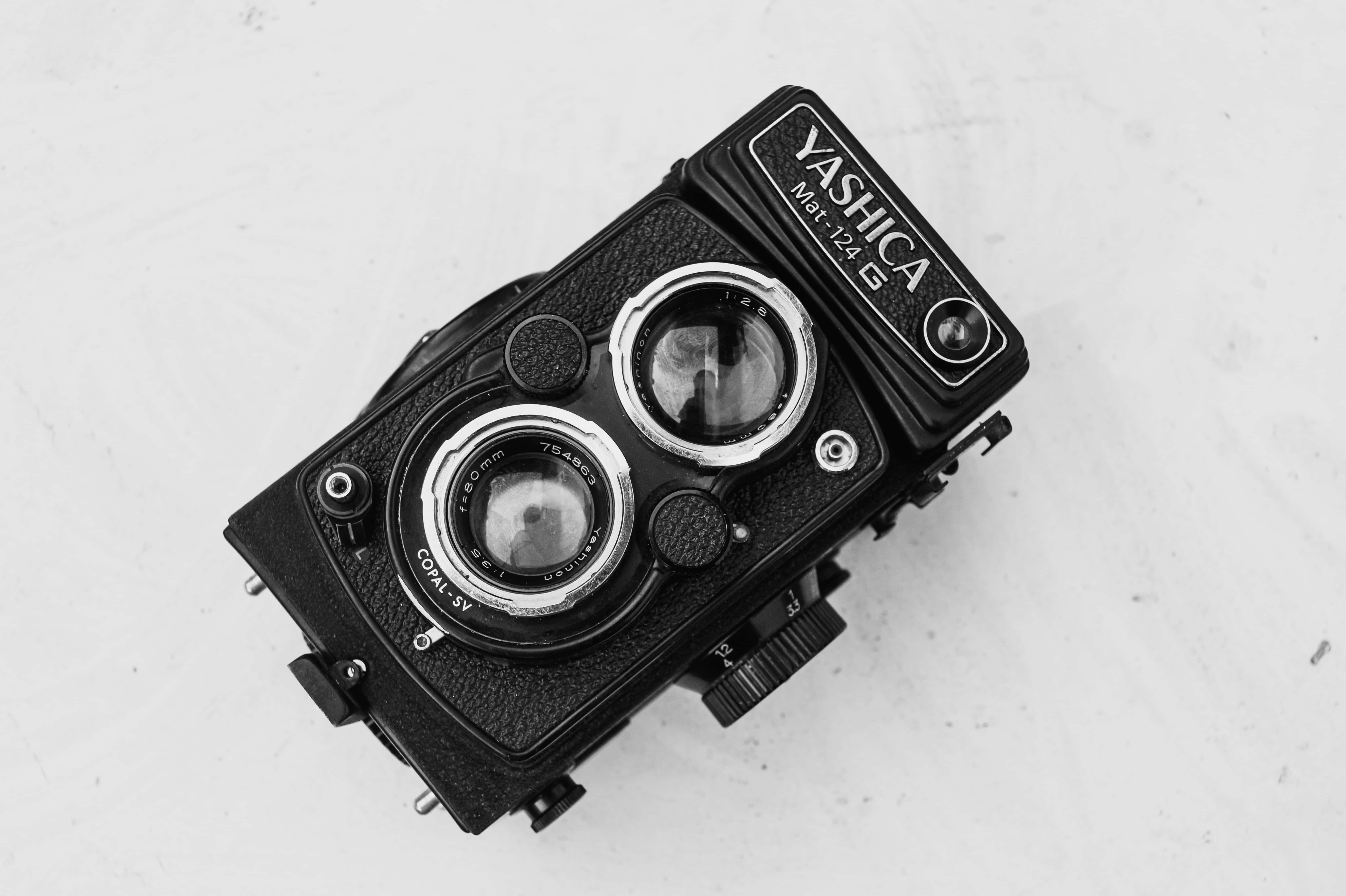 Aesthetic Black And White 桌布 壁紙 — 一部復古Yashica Mat 124G雙鏡反光相機放置在白色表面上，以單色呈現。