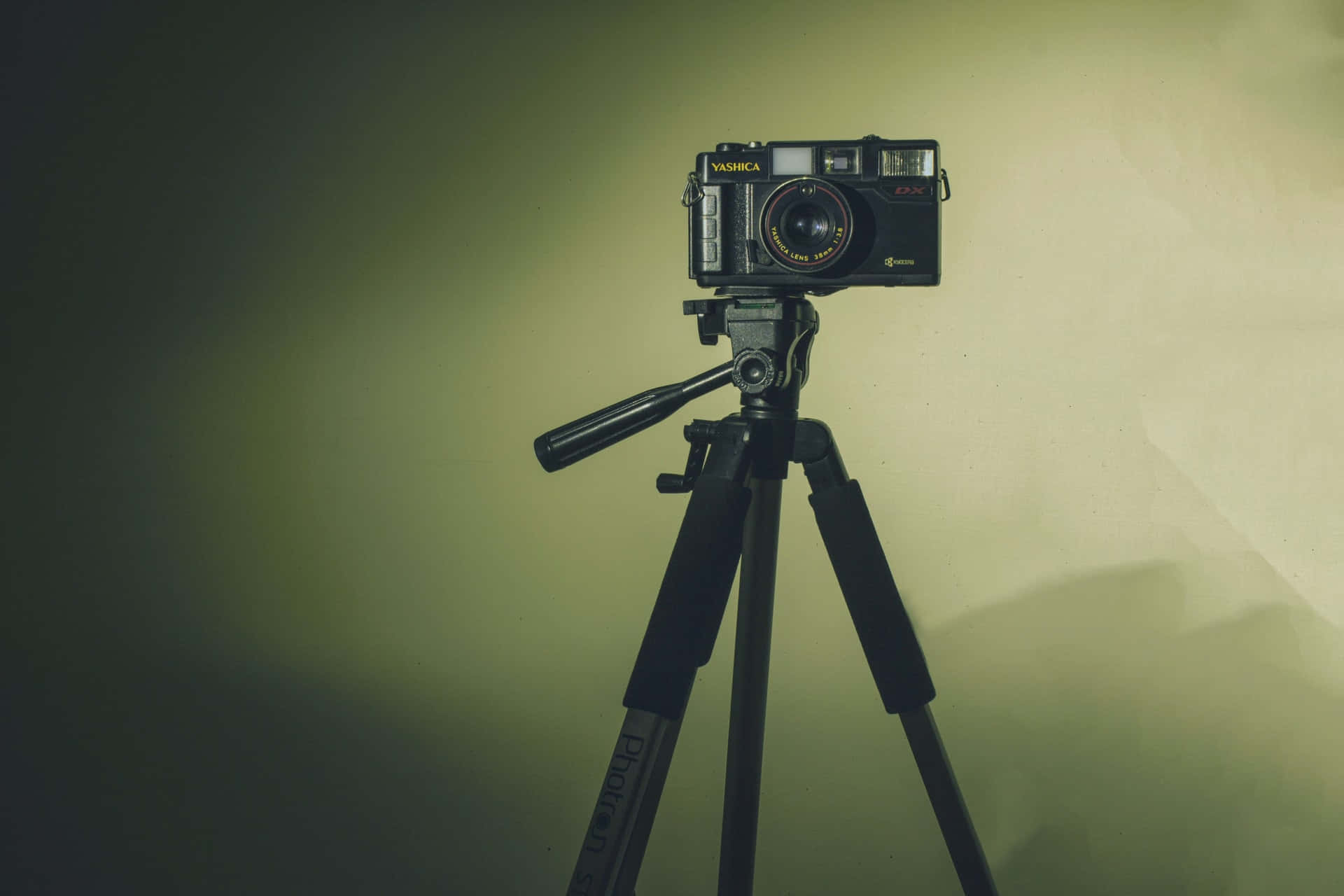 攝影師 桌布 壁紙 — 一部復古Yashica相機安裝在三腳架上，背景是柔和照明的綠色漸變牆。