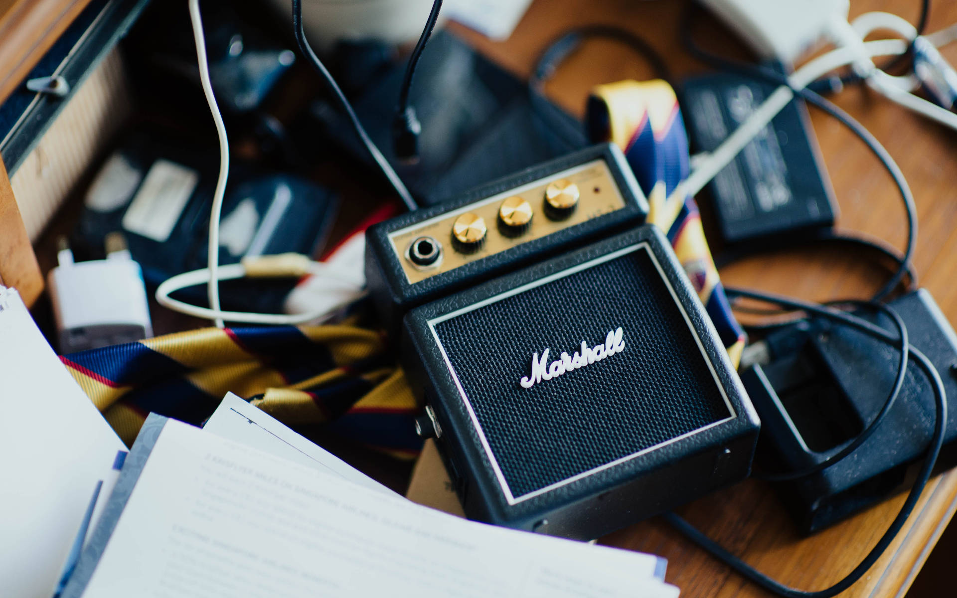 Marshall 桌布 壁紙 — 一部復古的Marshall吉他擴音器安放在木桌上，周圍纏繞著電線、紙張和科技設備。