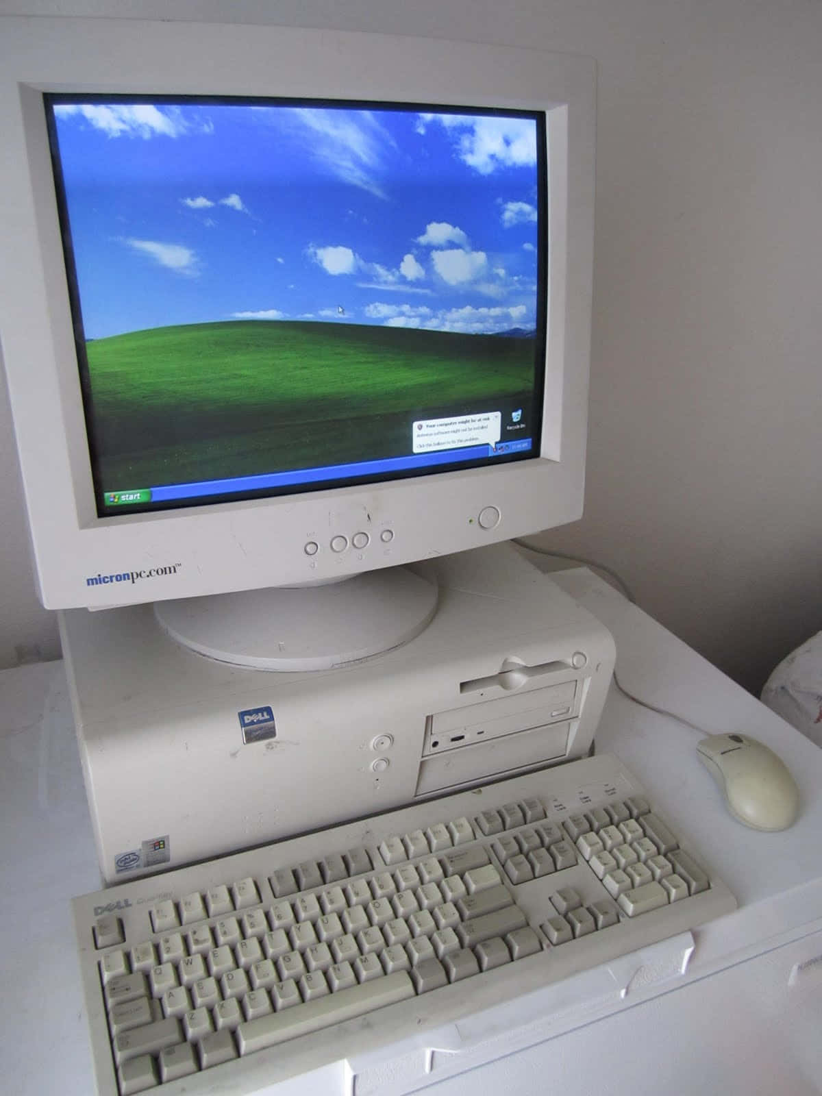 machines 桌布 壁紙 — 一部復古米色 Dell 桌上型電腦，顯示器上顯示經典的綠色山丘桌布。