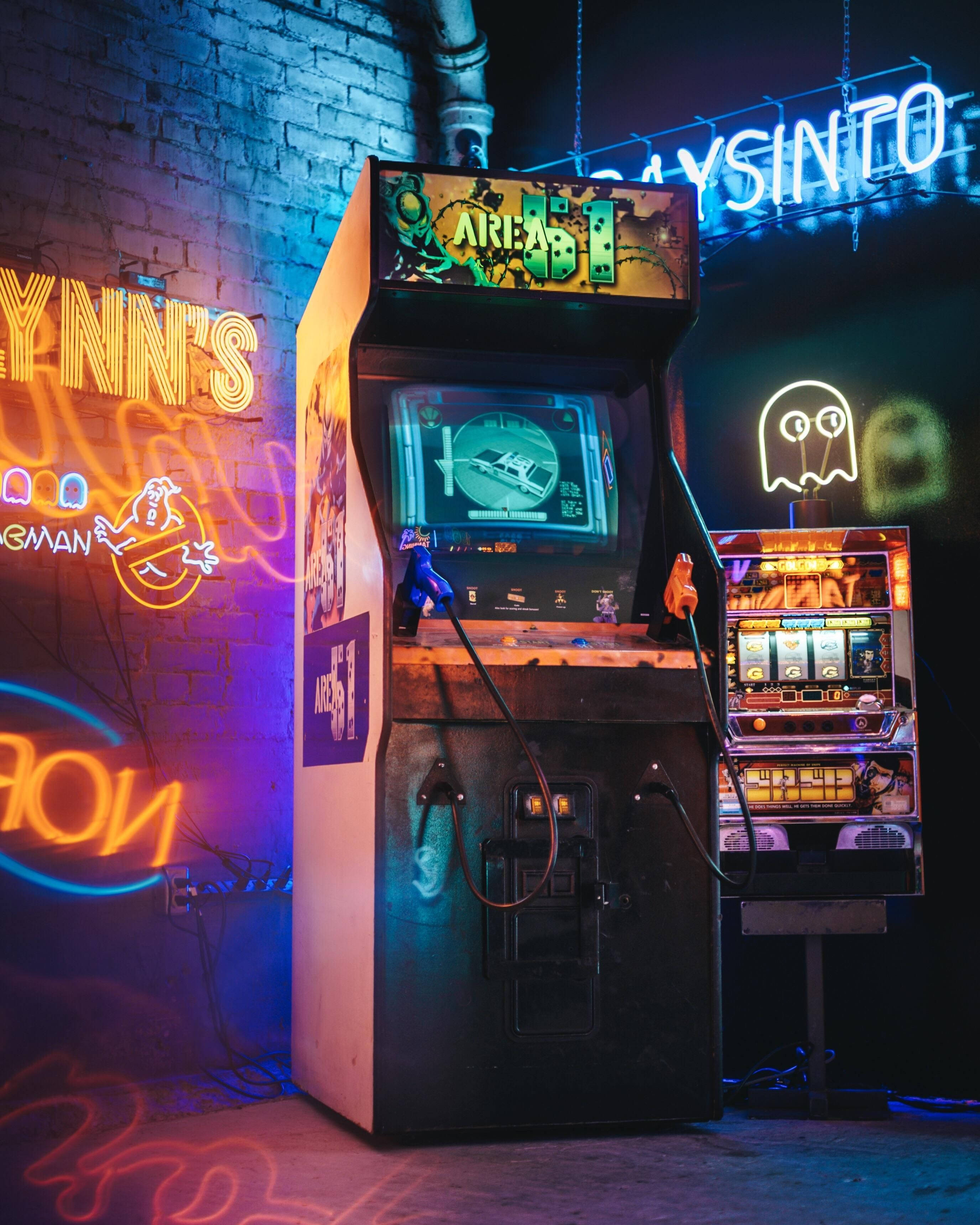 arcade 桌布 壁紙 — 一部復古街機在霓虹燈牌下發光，身處一個滿佈塗鴉和發光鬼魂的粗獷復古遊戲廳。