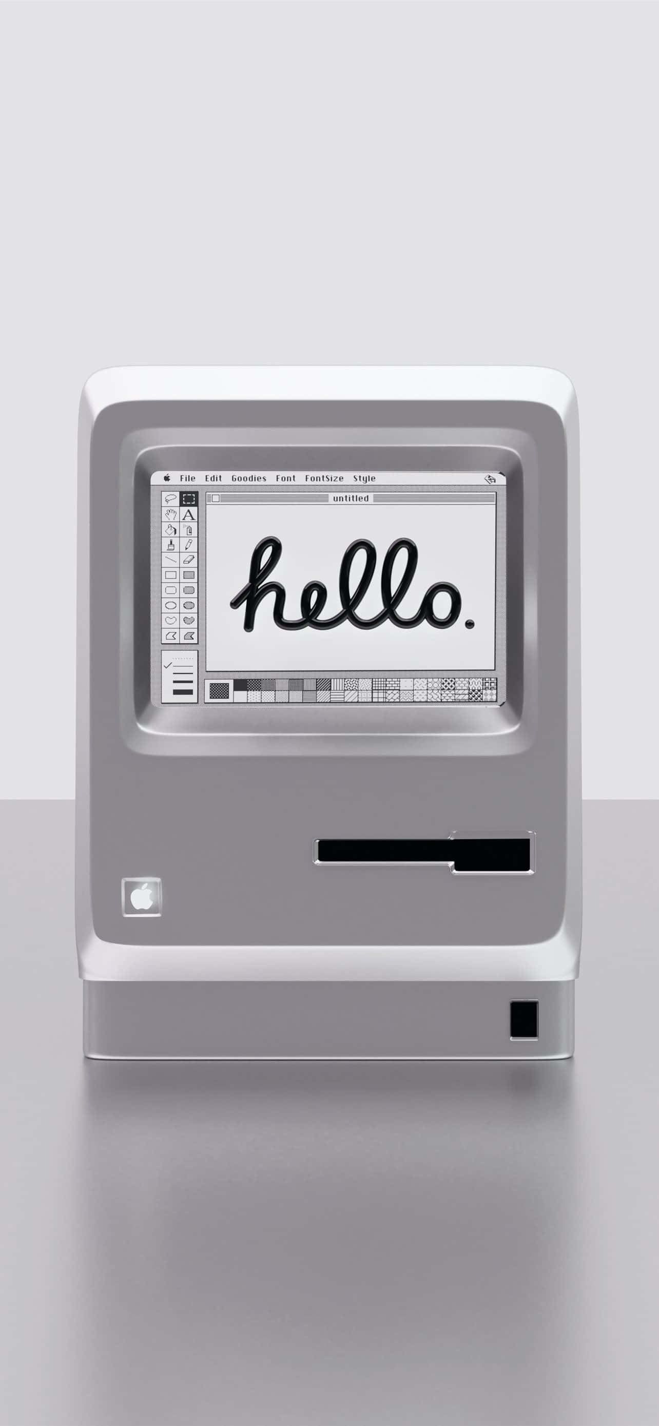 電子 桌布 壁紙 — 一部復古銀色 iMac G3 電腦在極簡灰色背景上，以手寫字體在螢幕上顯示「hello」一詞。